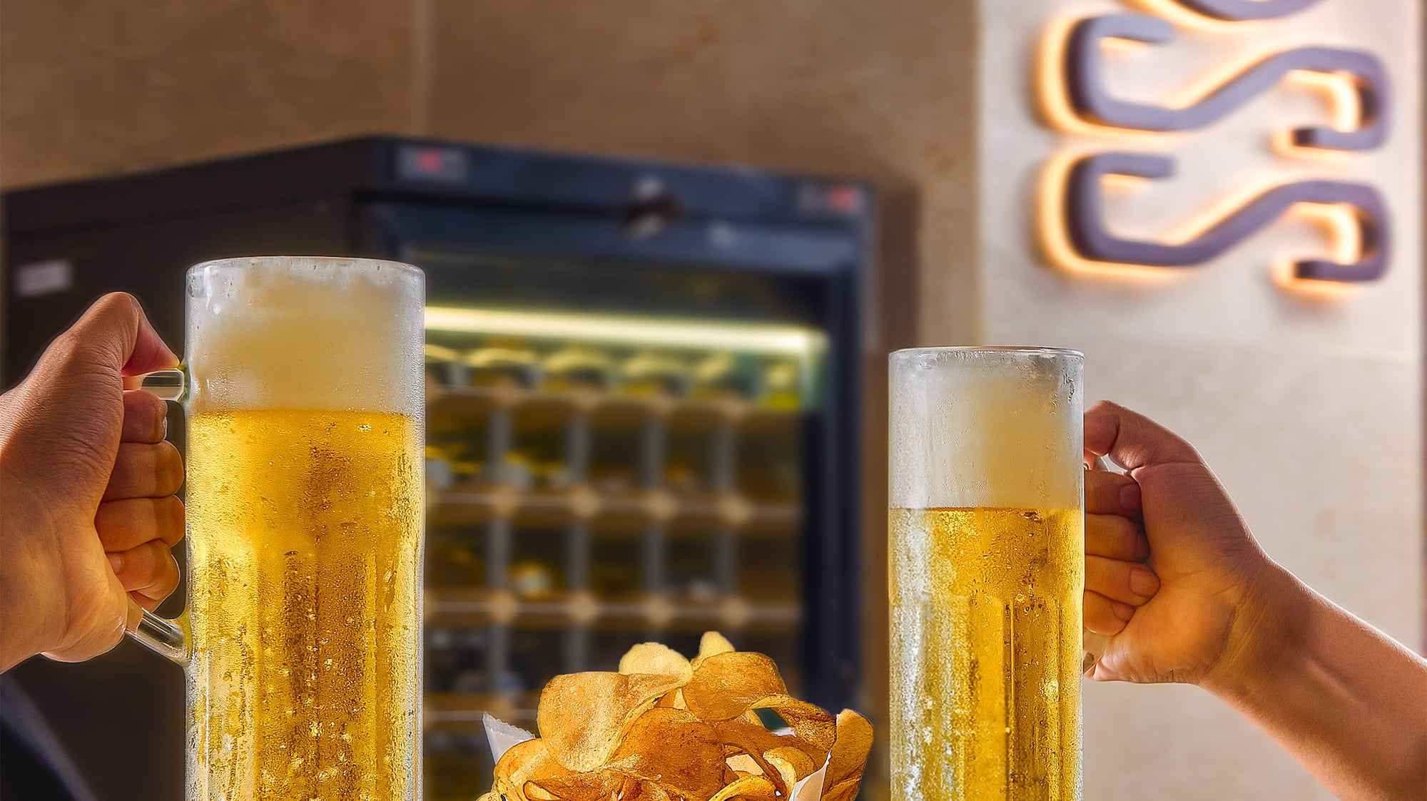 a person holding glasses of beer and a basket of chips