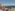 Resort dining terrace overlooking ocean, hotel pool, and distant mountains.