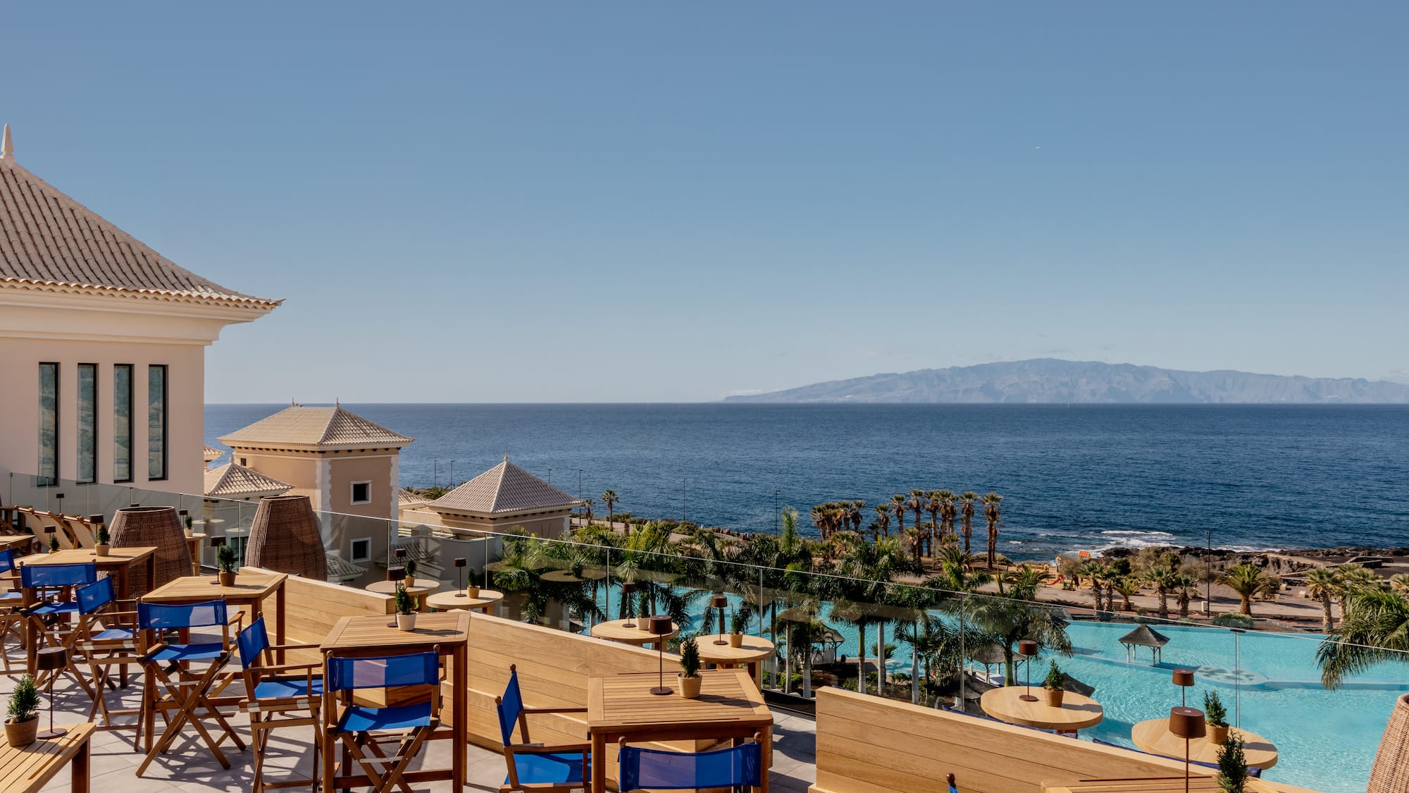 a patio with chairs and a pool overlooking a body of water