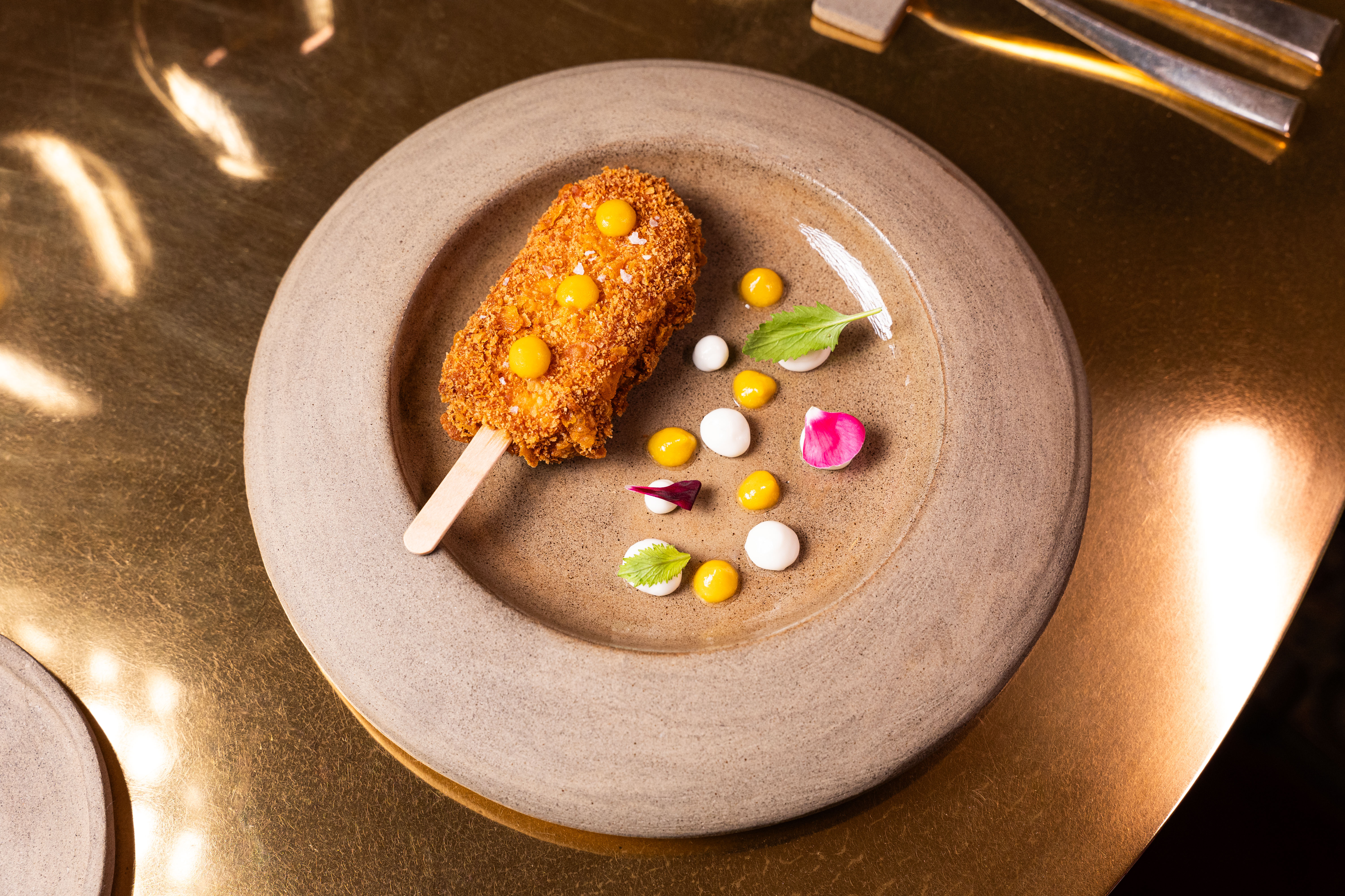 Gourmet fried appetizer with sauces and garnishes on rustic plate.
