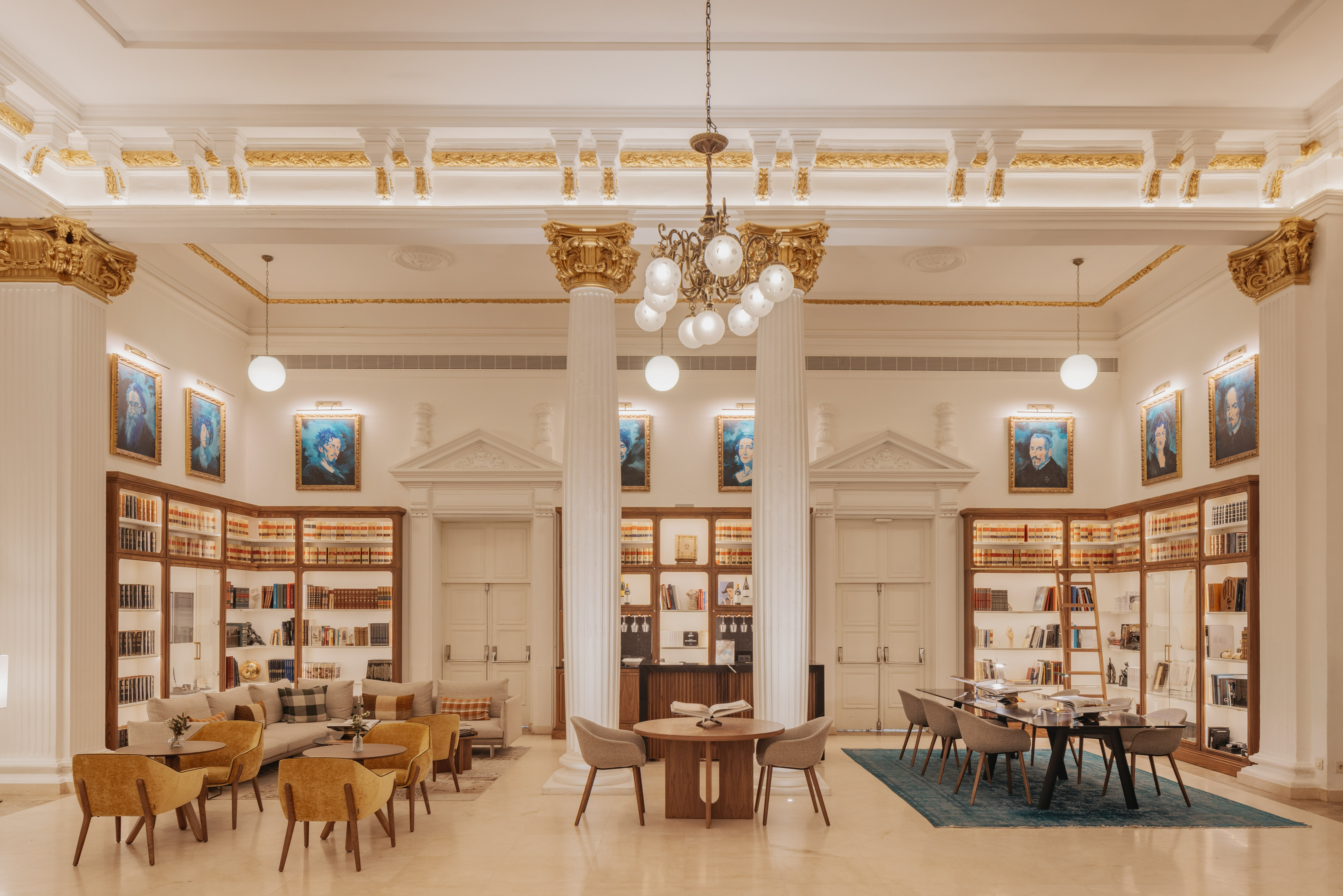 Grand library lounge with ornate columns, bookshelves, and elegant seating.
