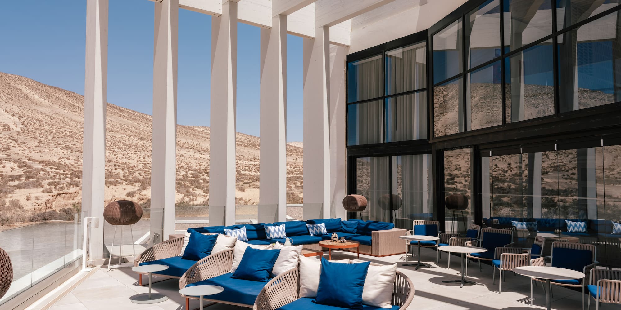 Modern desert resort outdoor lounge with blue seating and white pergola.