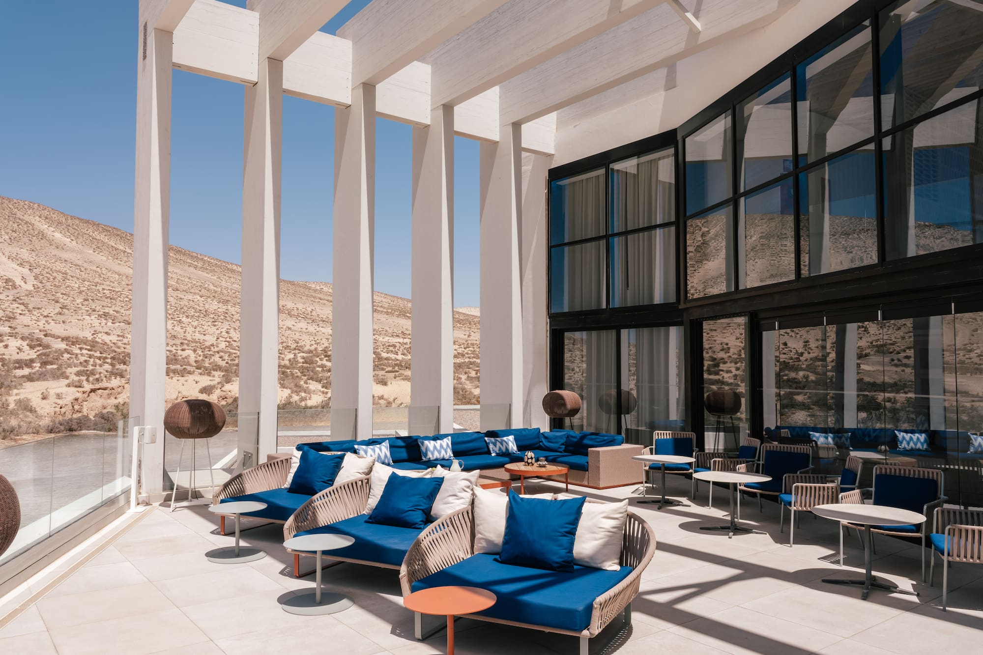 Modern desert resort outdoor lounge with blue seating and white pergola.