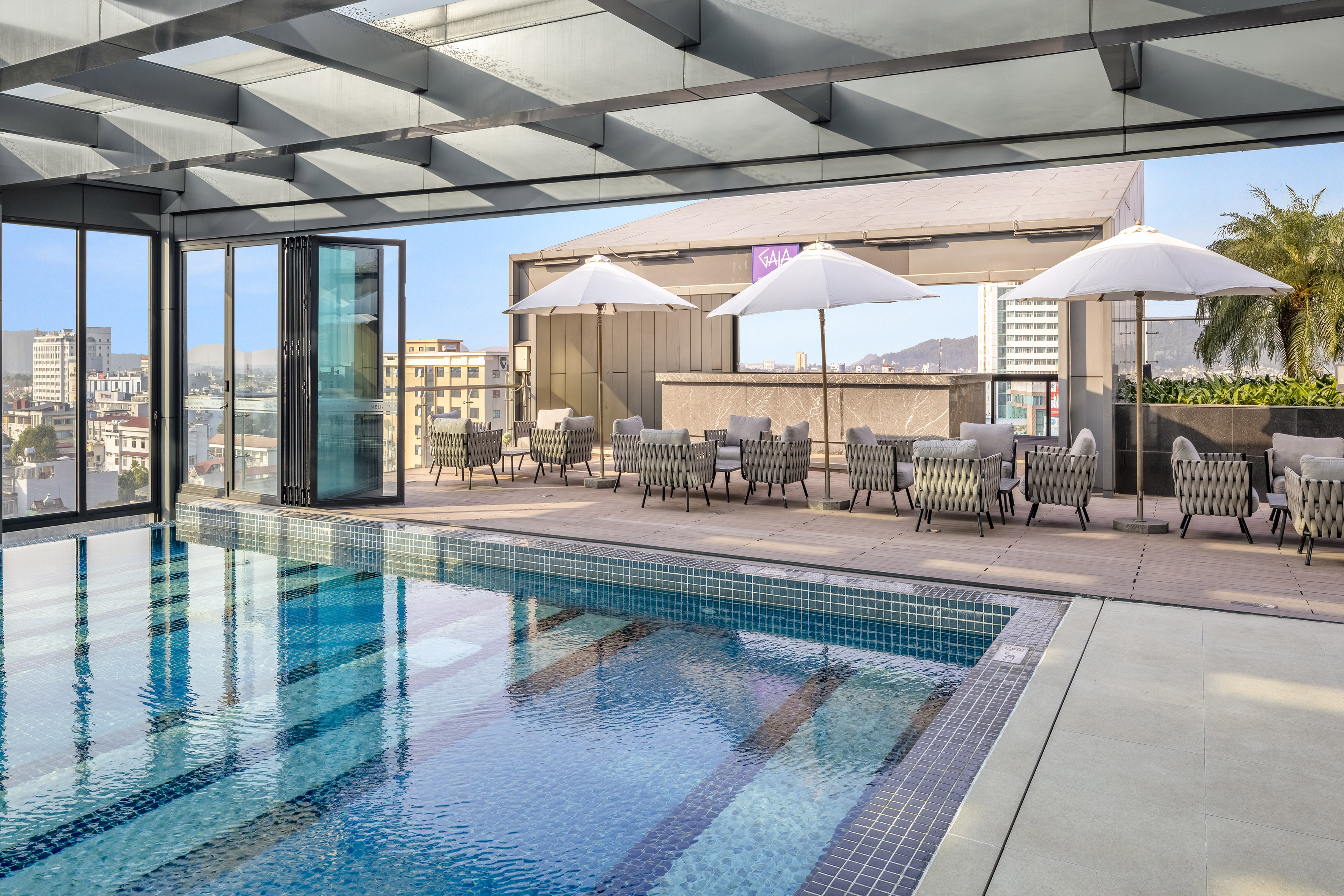 Modern rooftop pool deck with lounge, umbrellas, and city view.