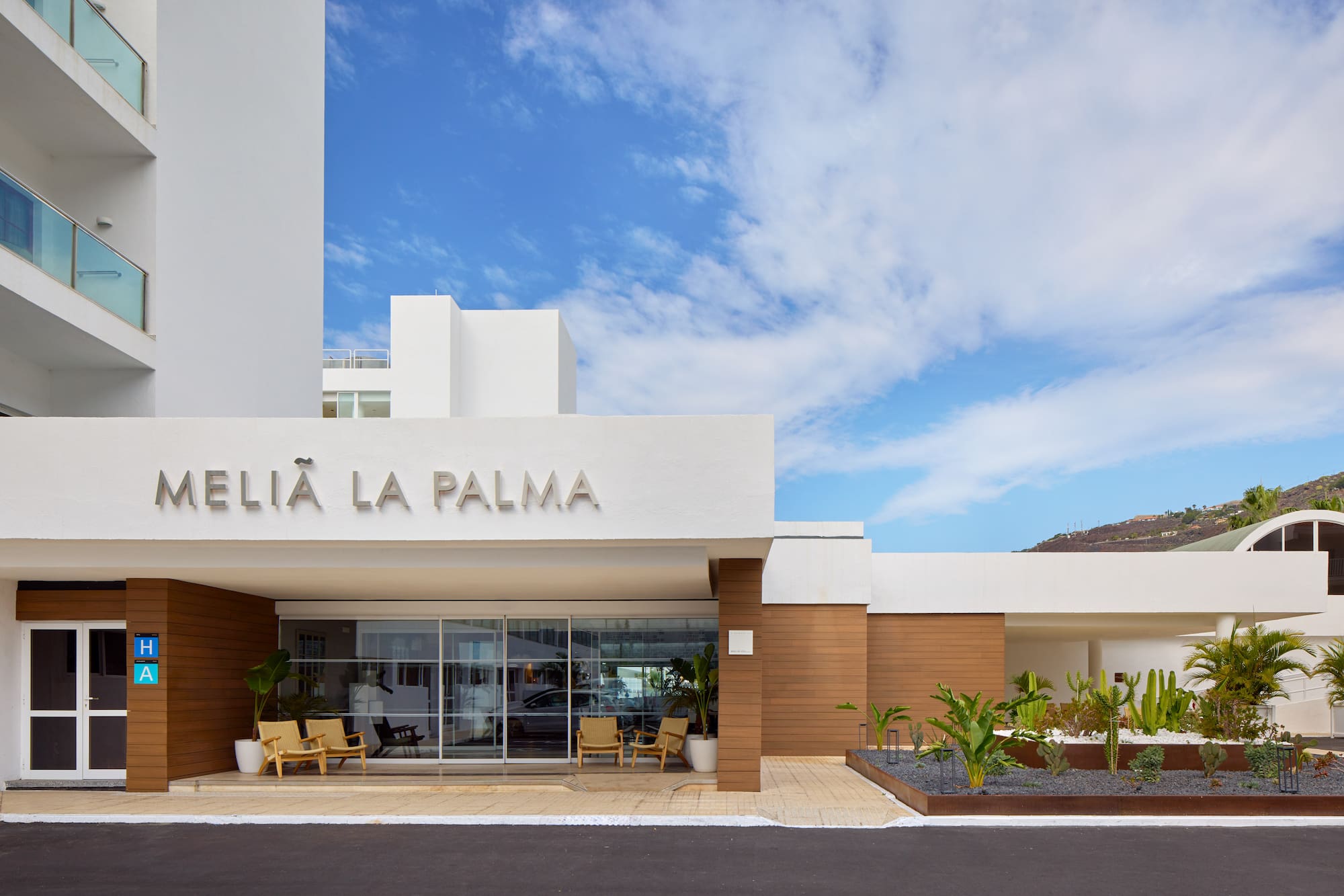 Meliá La Palma hotel entrance: modern white building, glass doors, tropical plants.