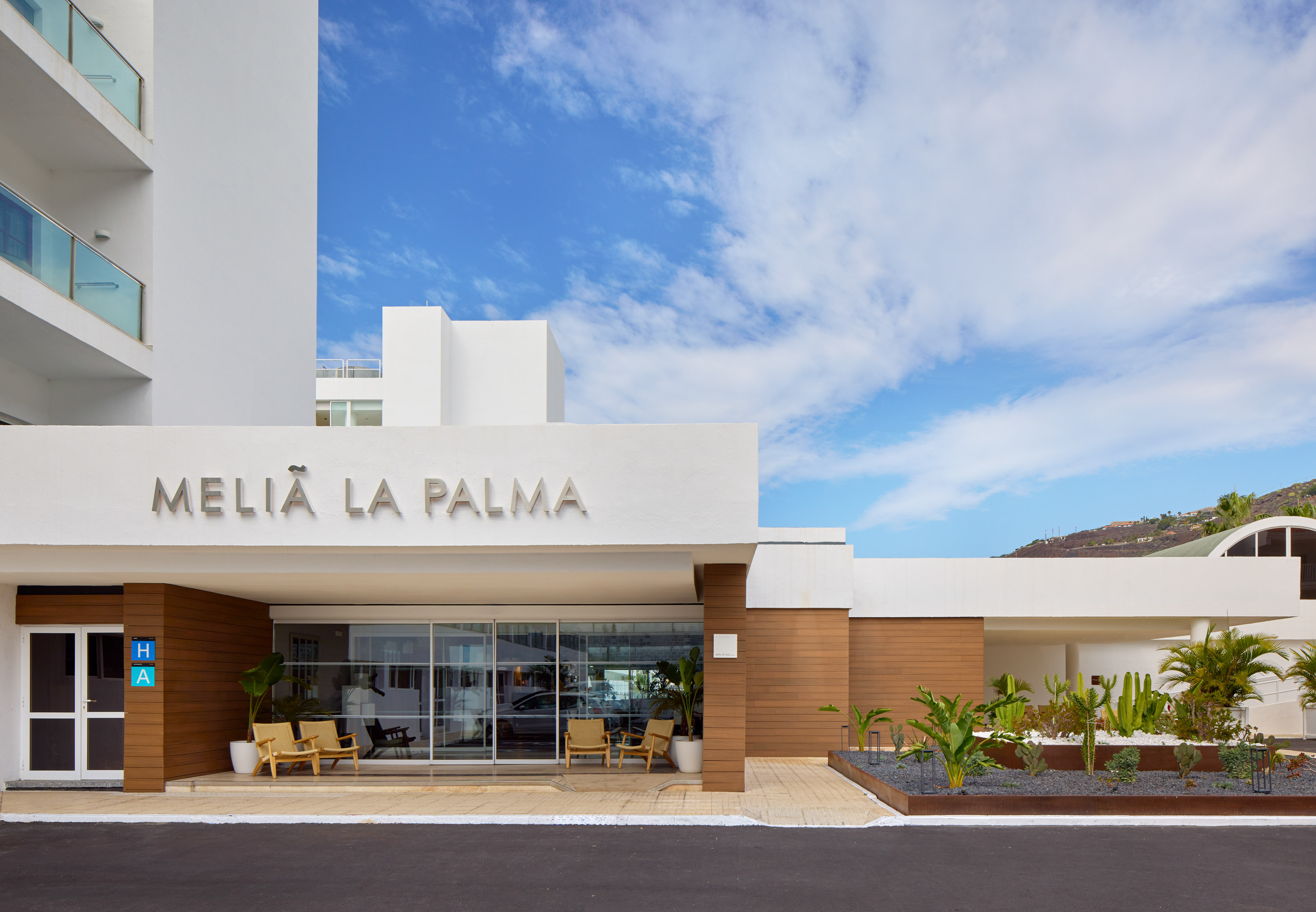 Meliá La Palma hotel entrance: modern white building, glass doors, tropical plants.
