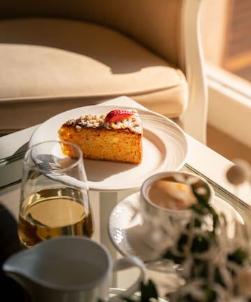 a piece of cake on a plate next to a cup of coffee