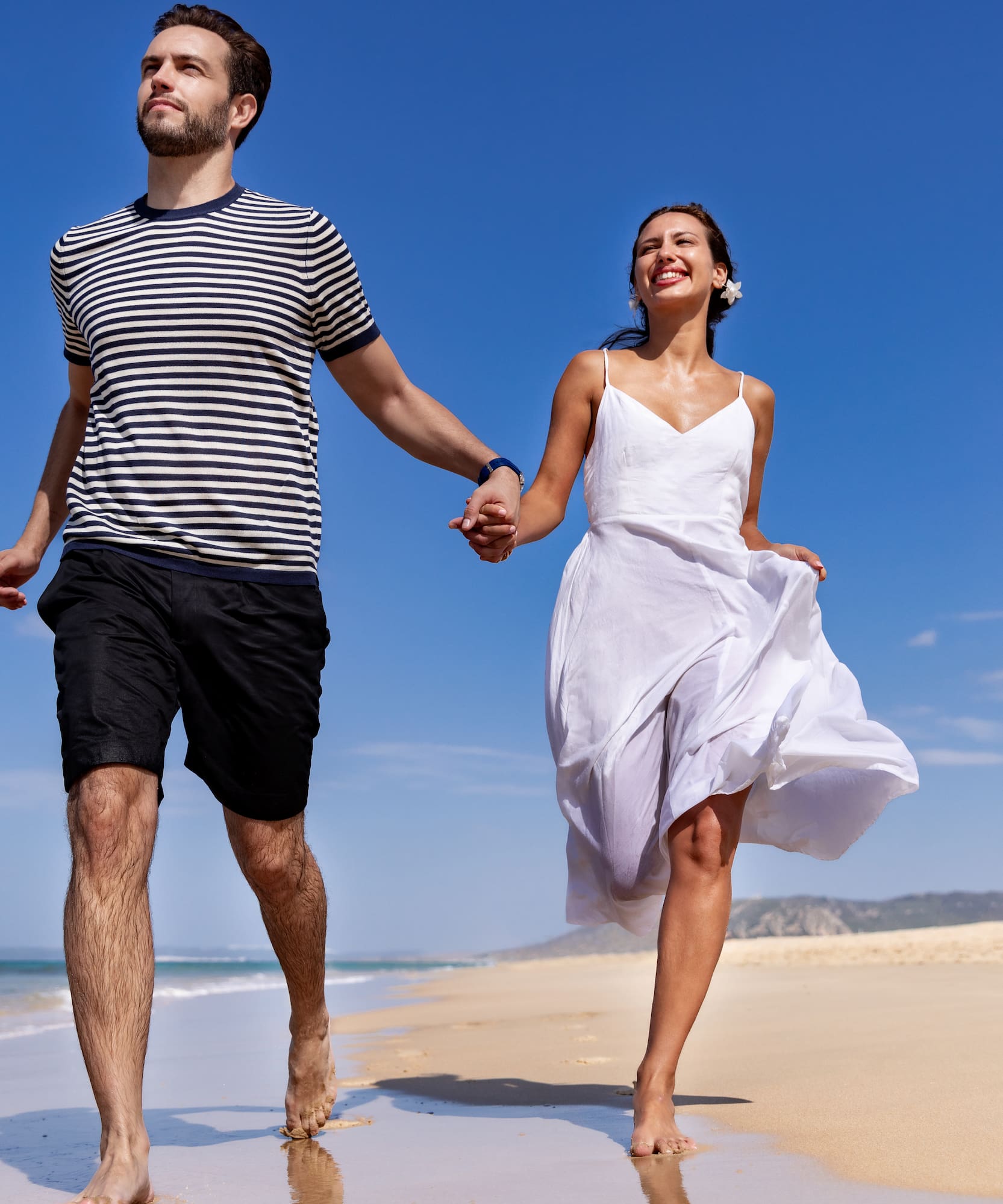 a man and woman holding hands on a beach