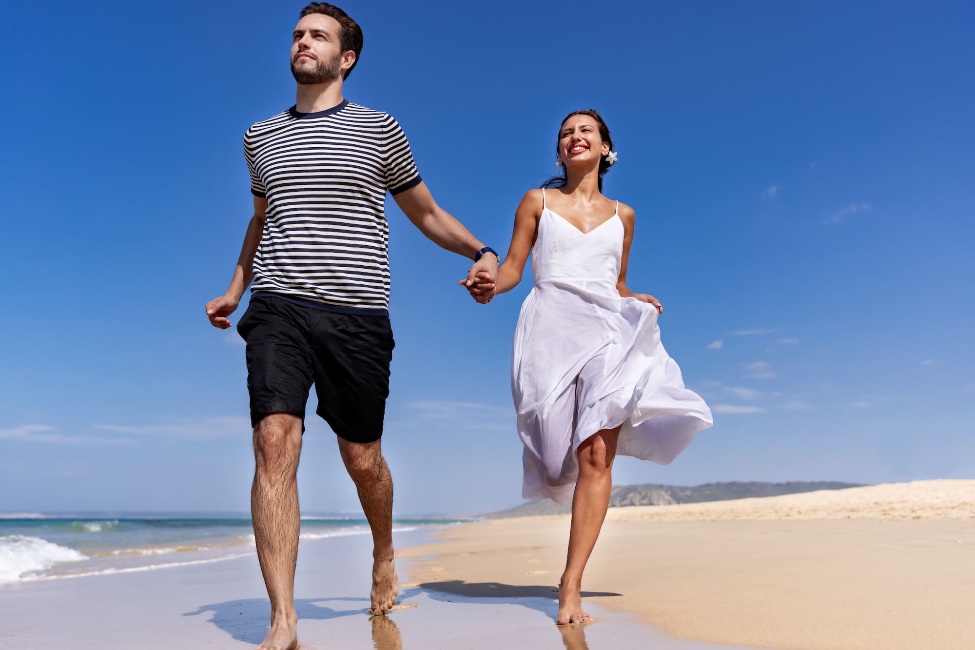 a man and woman holding hands on a beach