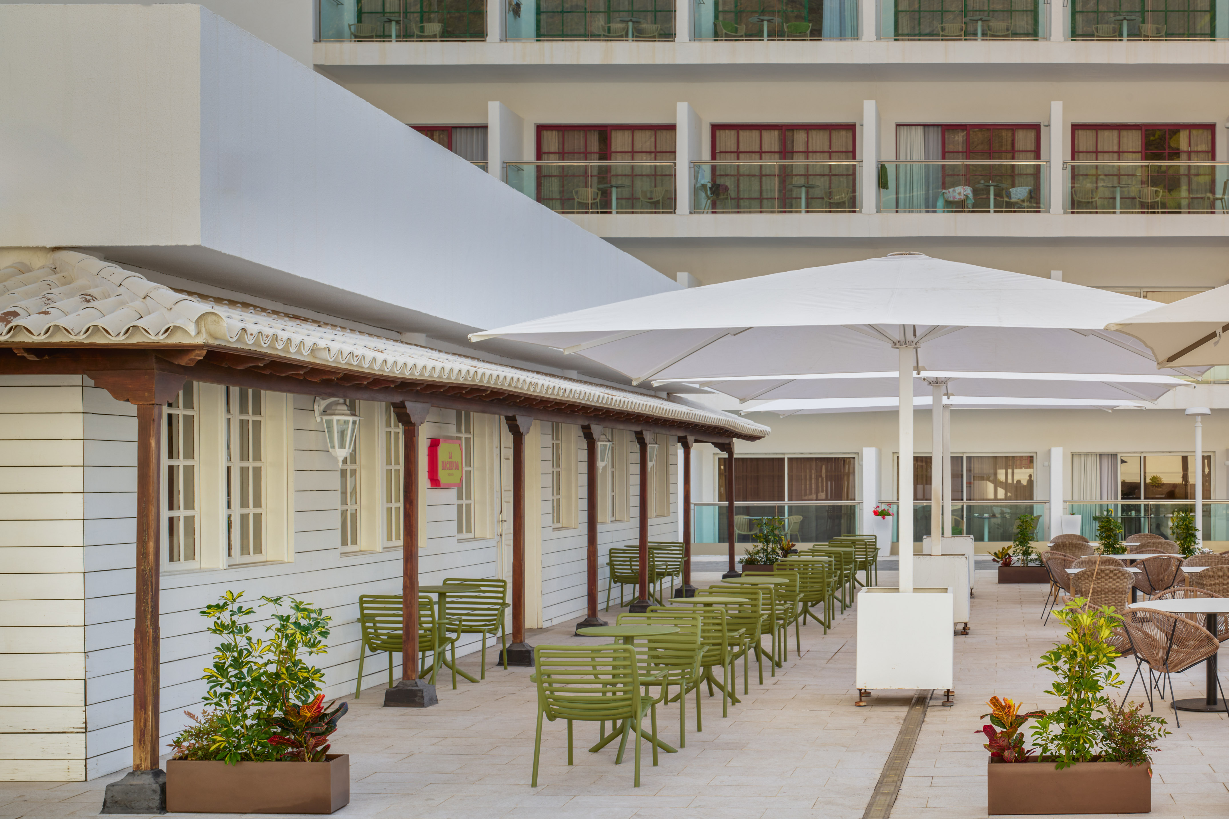 Hotel La Hacienda outdoor restaurant patio with green seating and white umbrellas.
