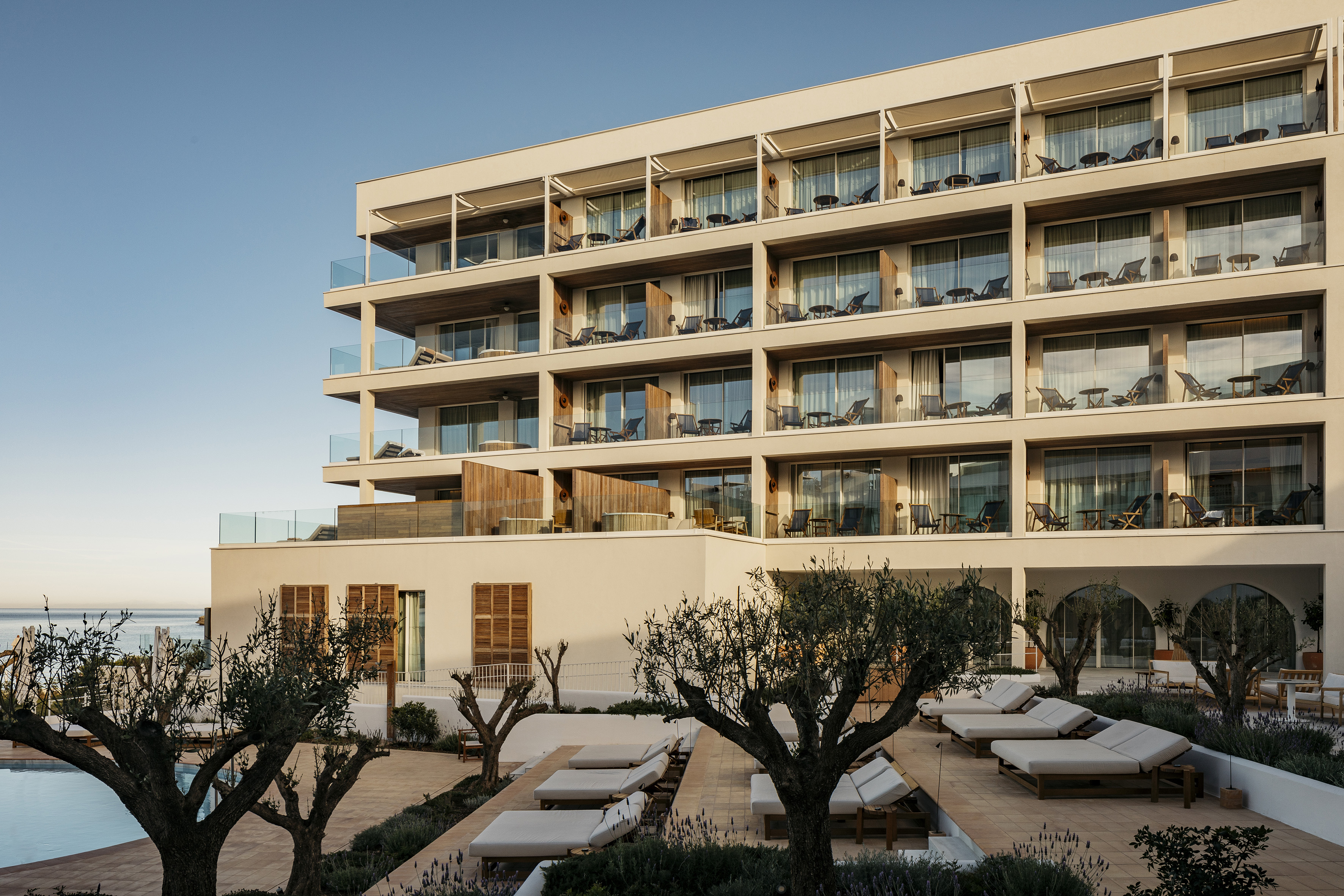 Luxury hotel with balconies, poolside loungers, and ocean view.