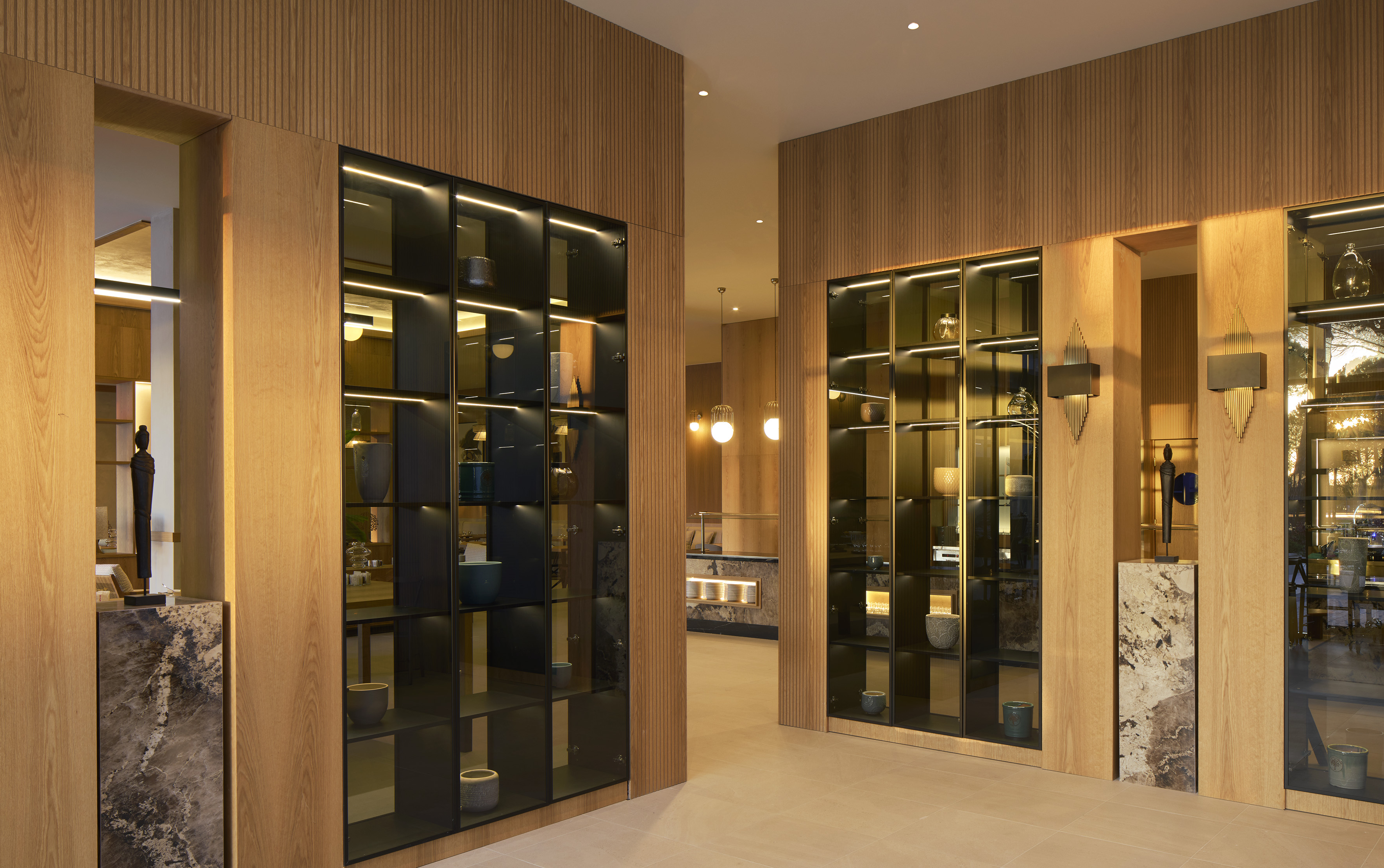 Contemporary lobby with wood paneling and illuminated glass display cabinets.