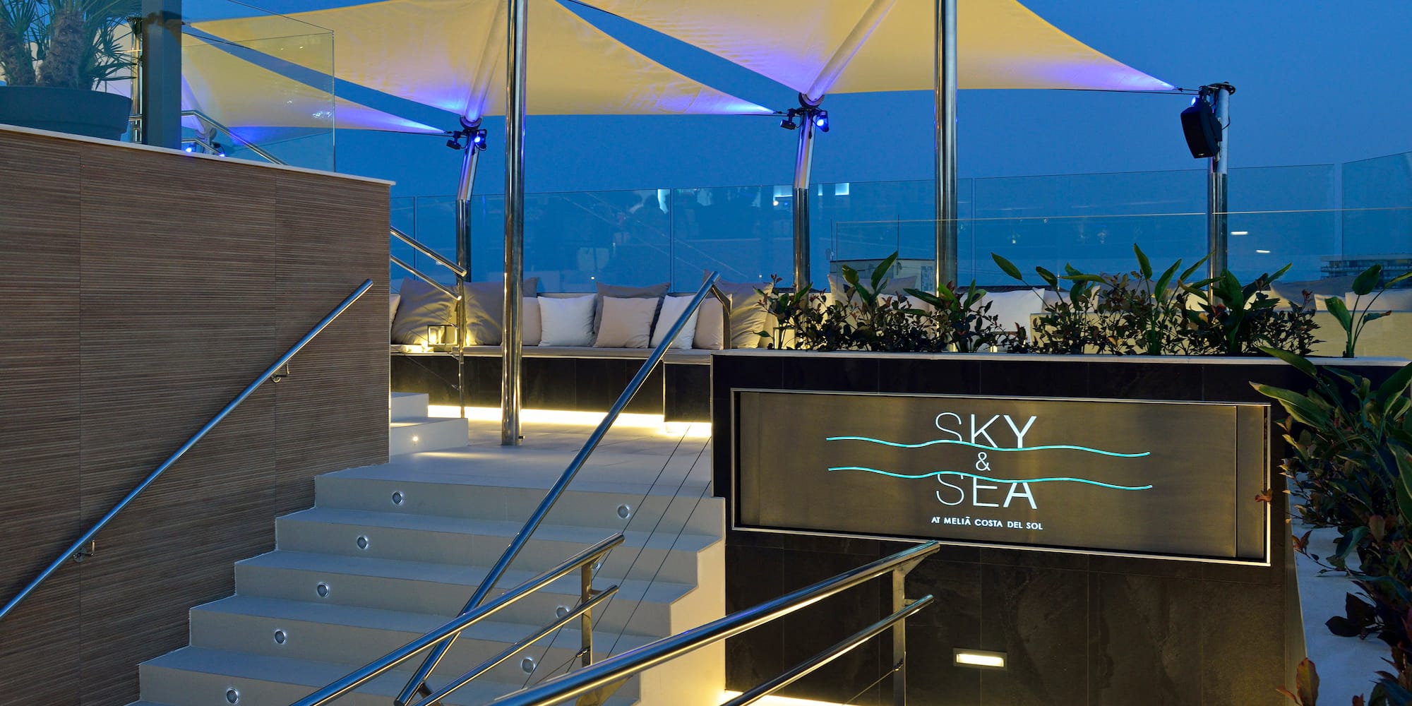 Sky & Sea rooftop bar entrance, illuminated stairs, modern canopy at dusk.