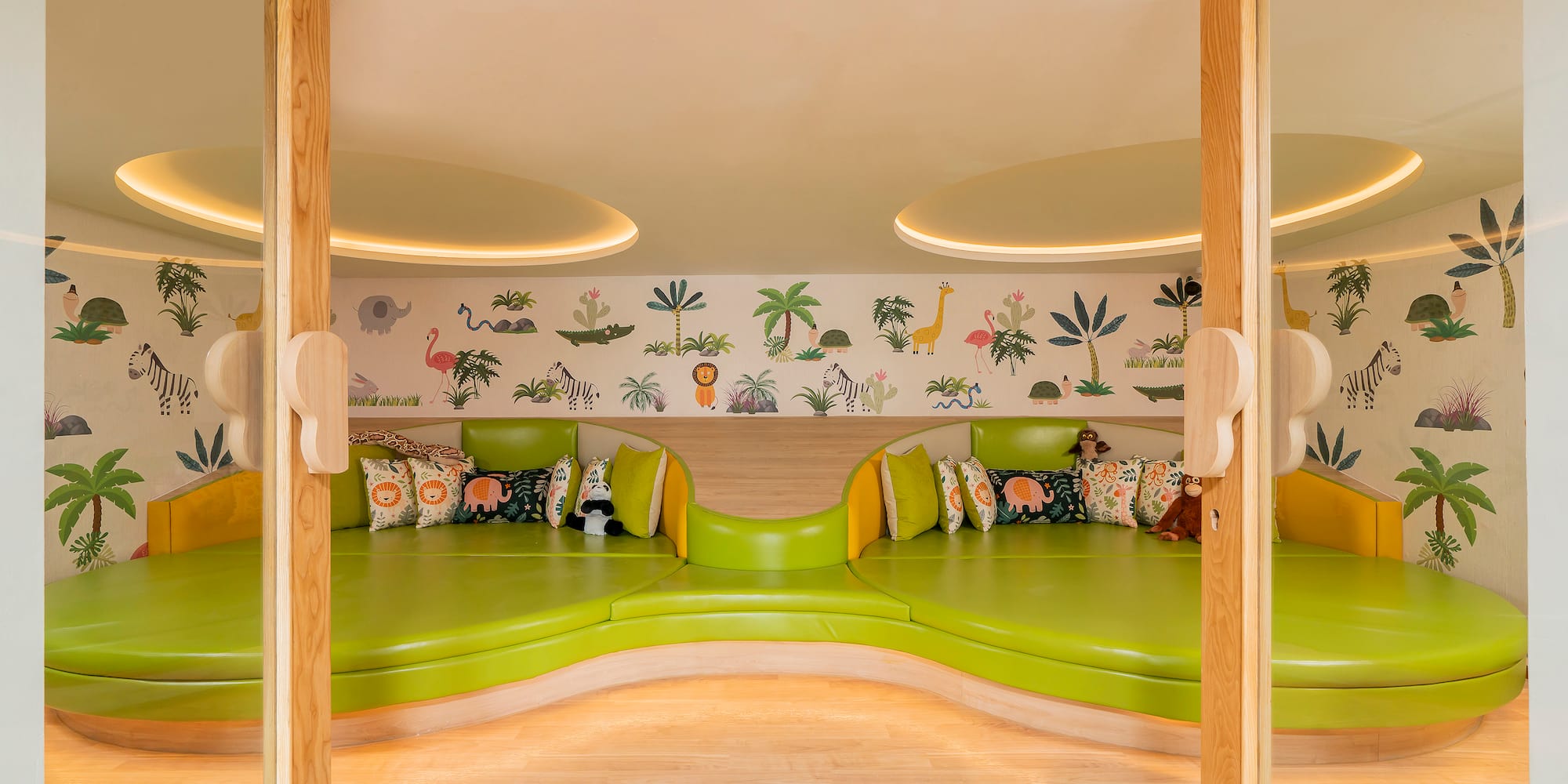 a room with green couches and a wall with animals