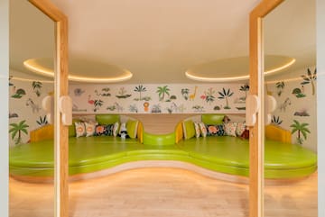 a room with green couches and a wall with animals