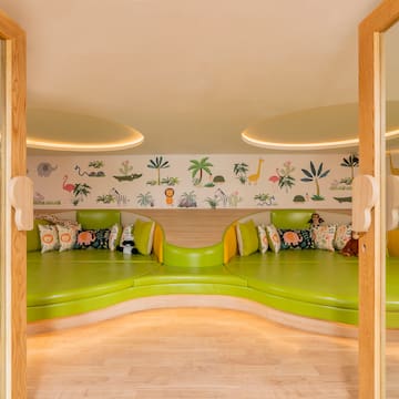 a room with green couches and a wall with animals