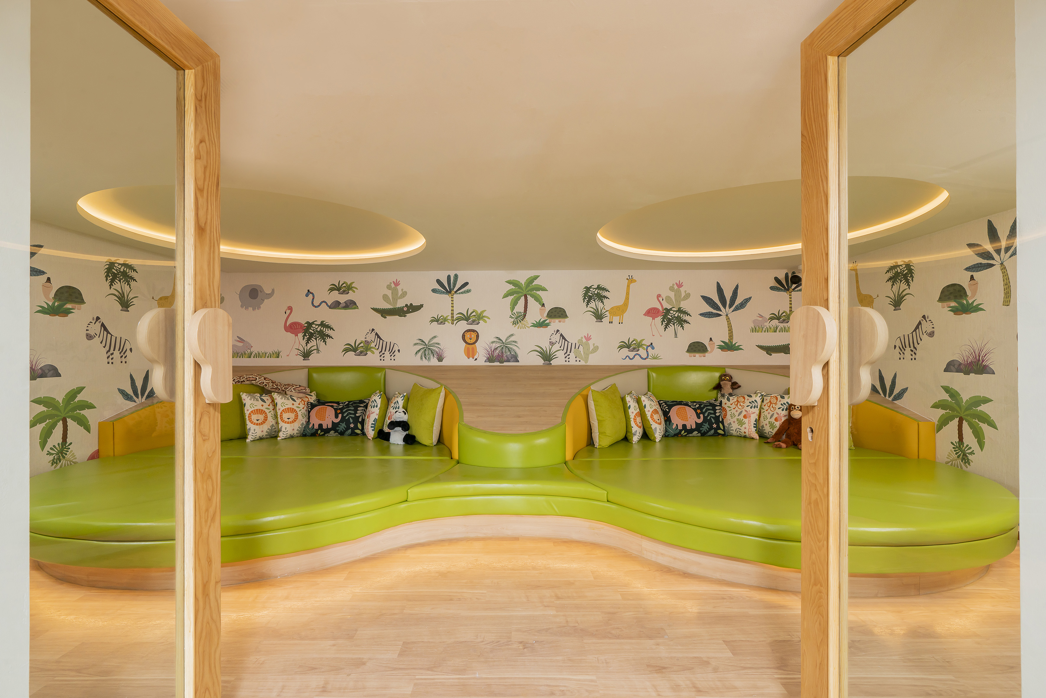 a room with green couches and a wall with animals