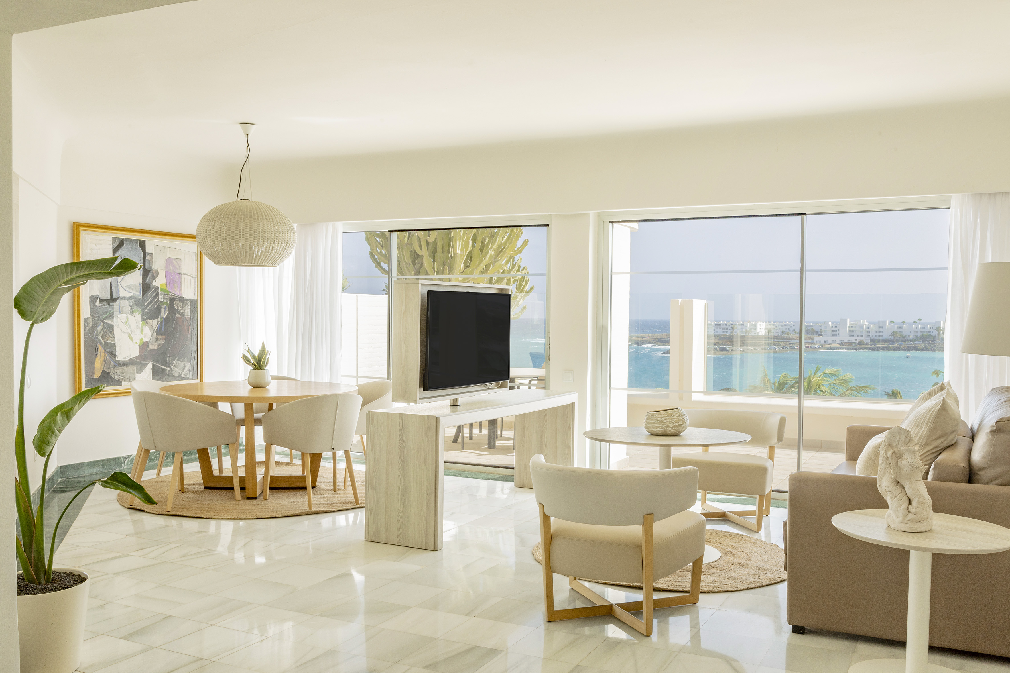 Bright modern living room with ocean view, dining area, and marble floor.