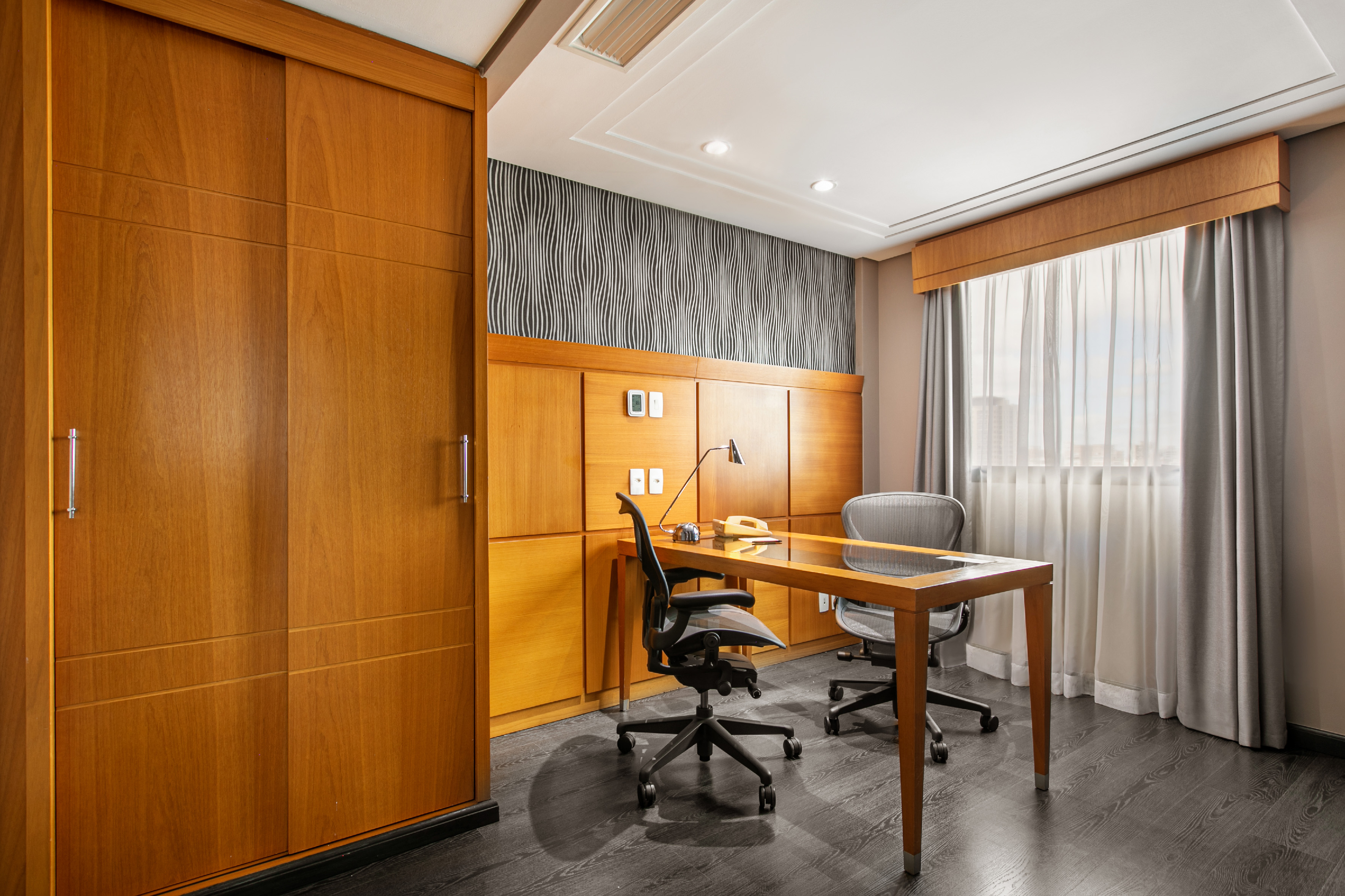 Modern office with wooden desk, ergonomic chairs, and integrated wood cabinetry.