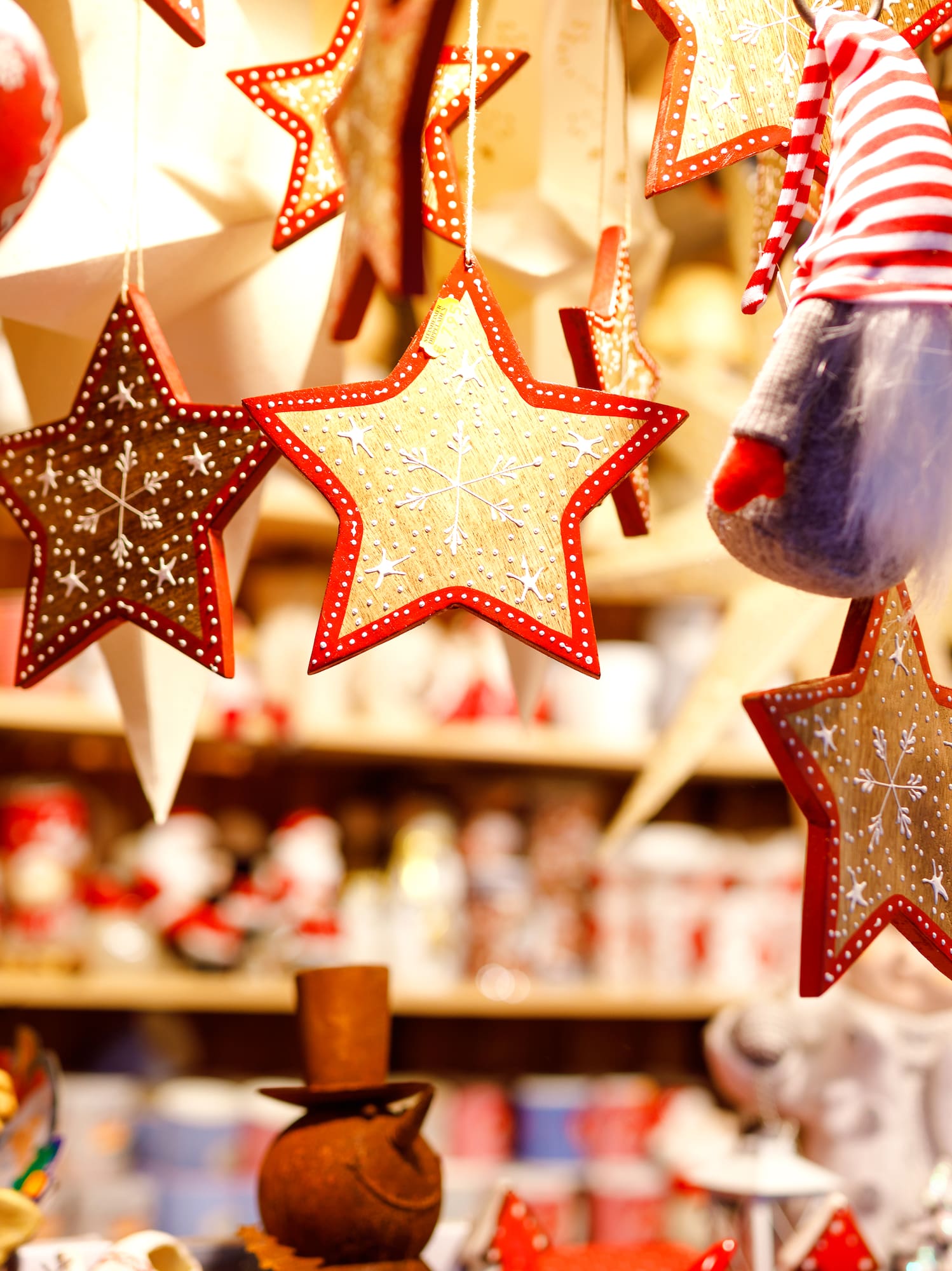 Hanging festive Christmas decorations: red hearts, golden stars, and a gnome.