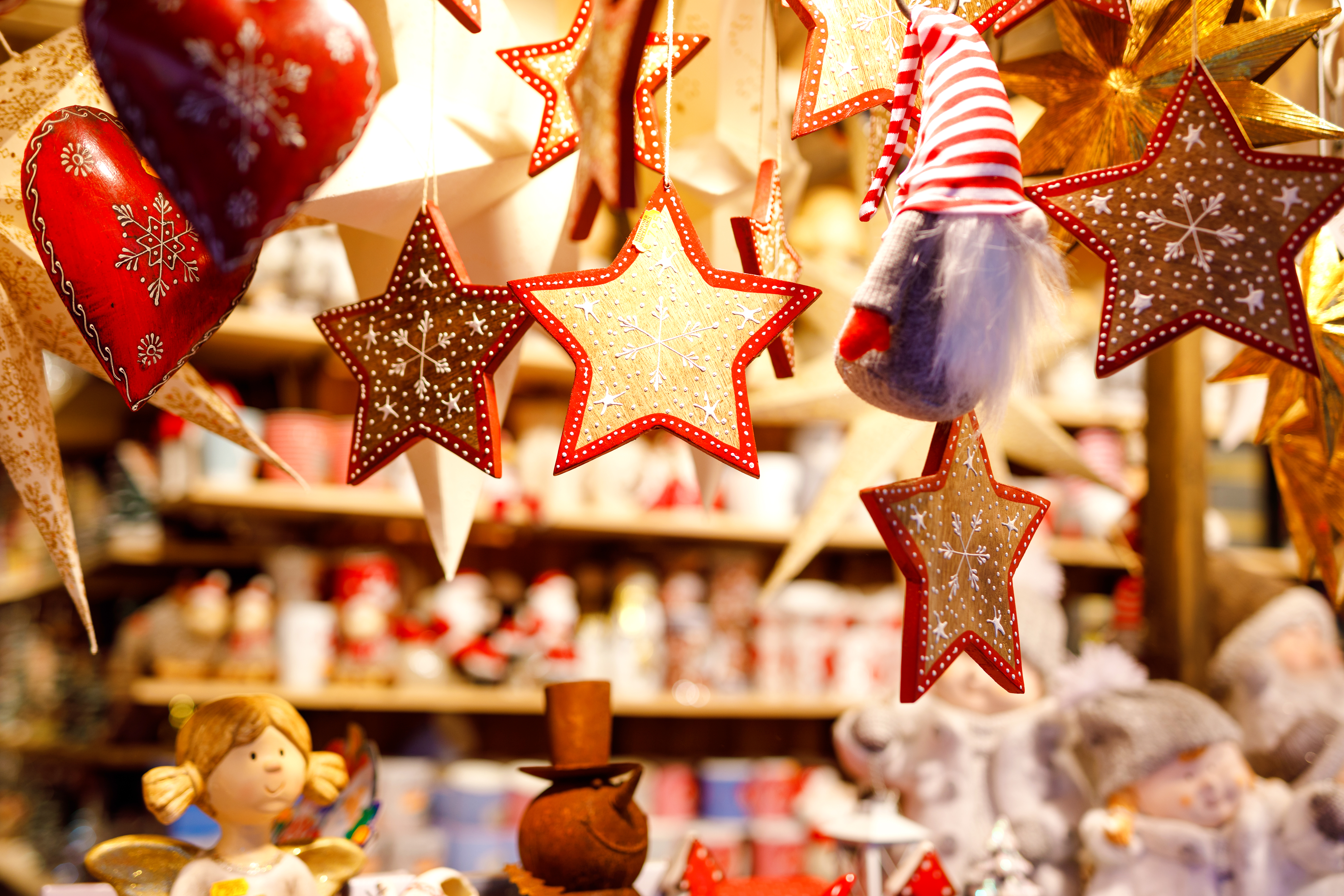 Hanging festive Christmas decorations: red hearts, golden stars, and a gnome.