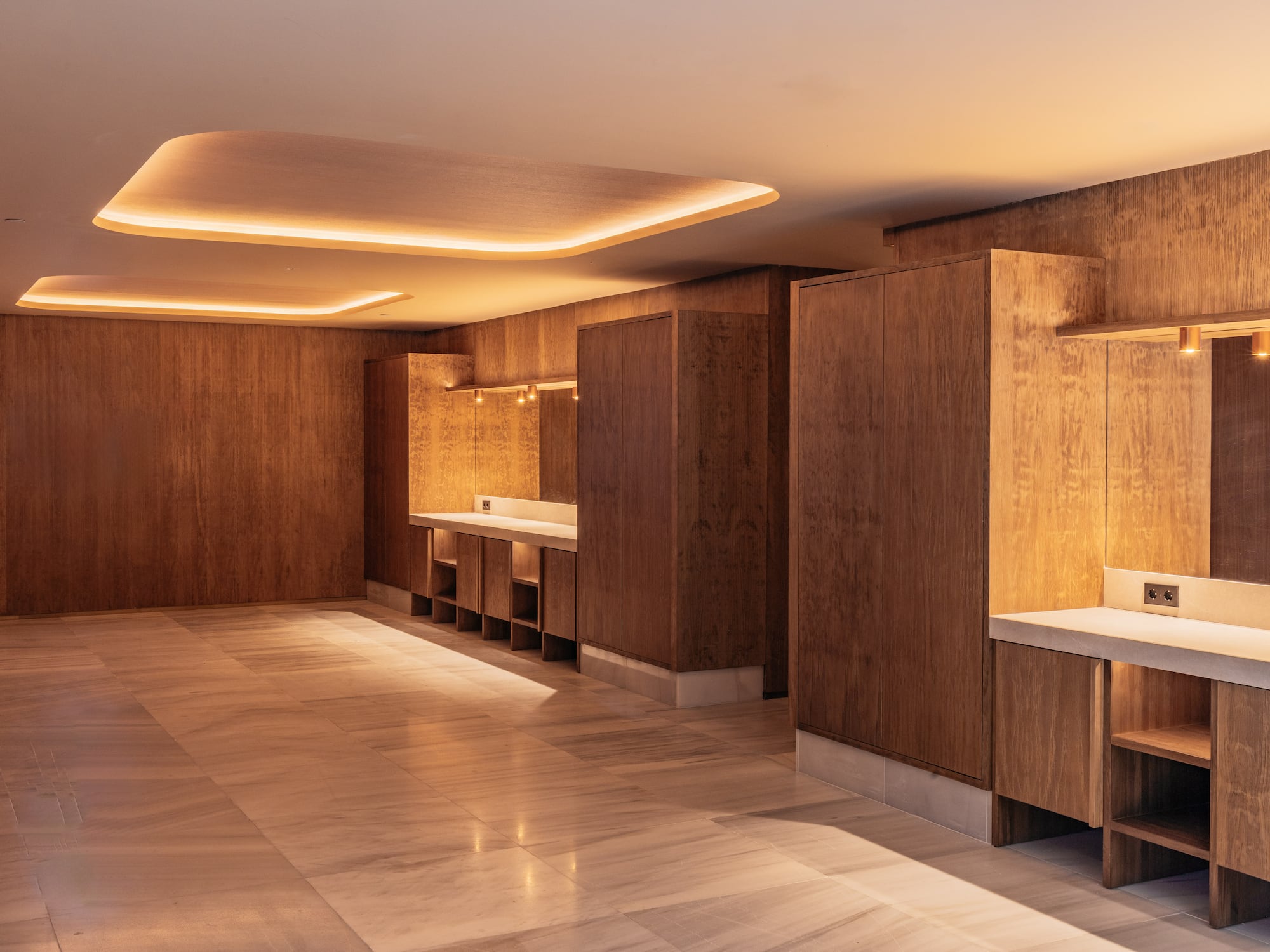 Modern wooden interior design with marble flooring and warm cove lighting.