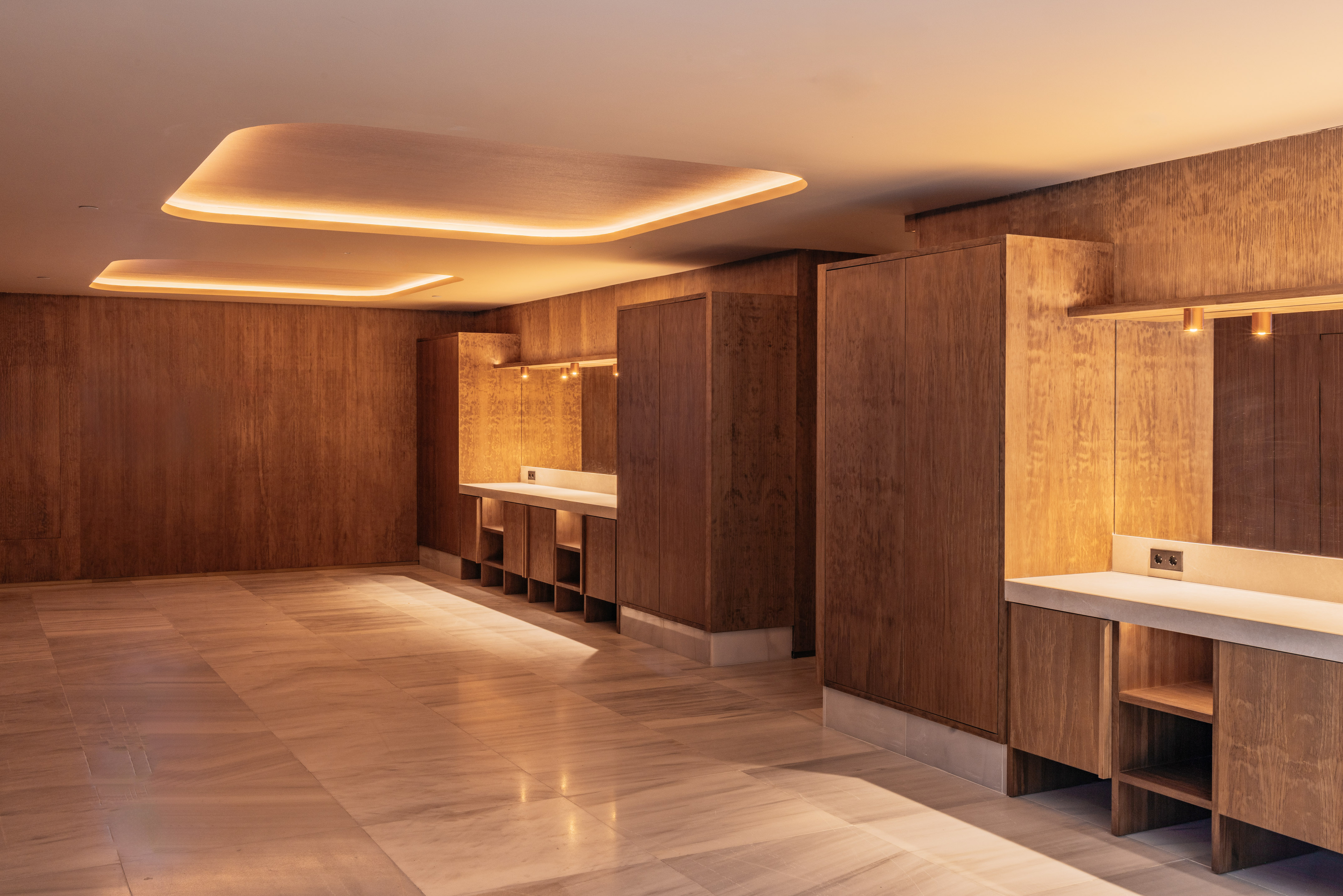 Modern wooden interior design with marble flooring and warm cove lighting.