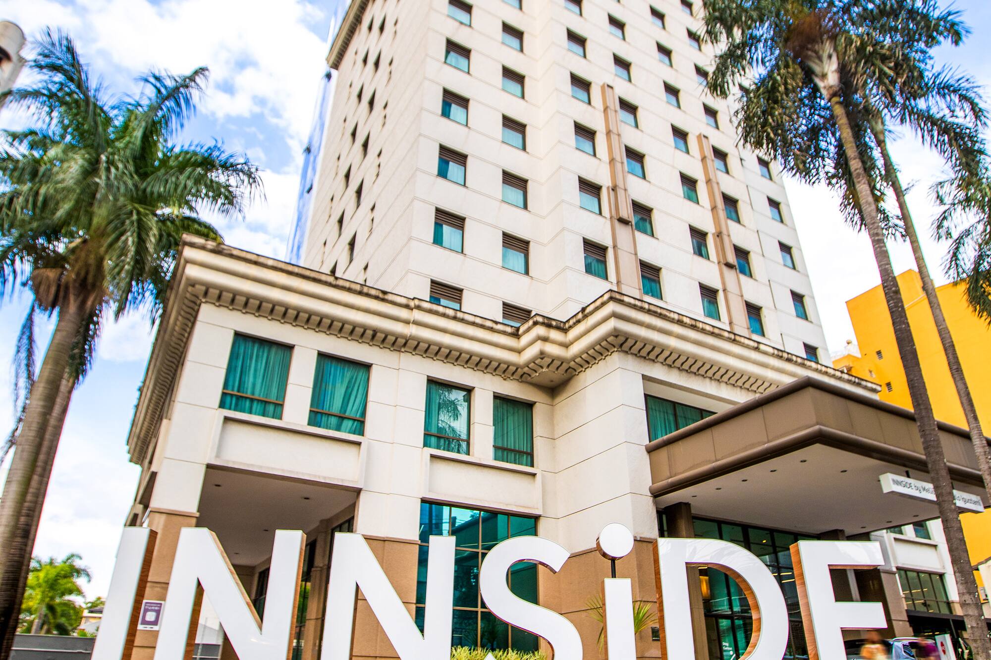 Tall INNSiDE by MELIÃ hotel building, prominent sign, and palm trees.