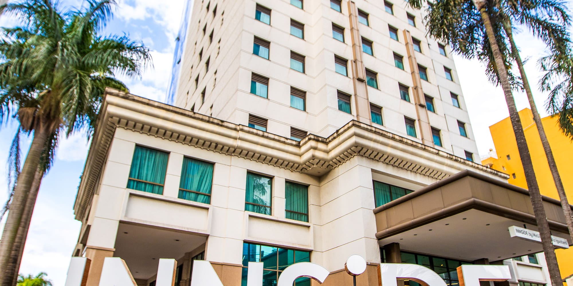 a building with palm trees and a sign