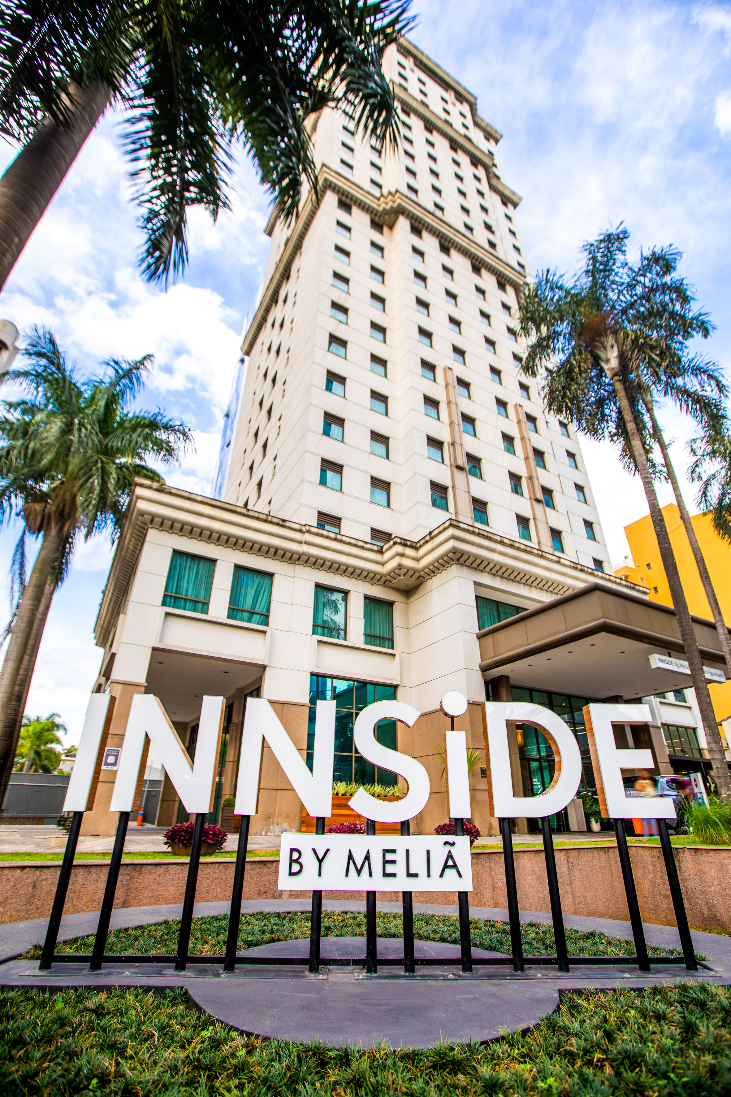 Tall INNSiDE by MELIÃ hotel building, prominent sign, and palm trees.