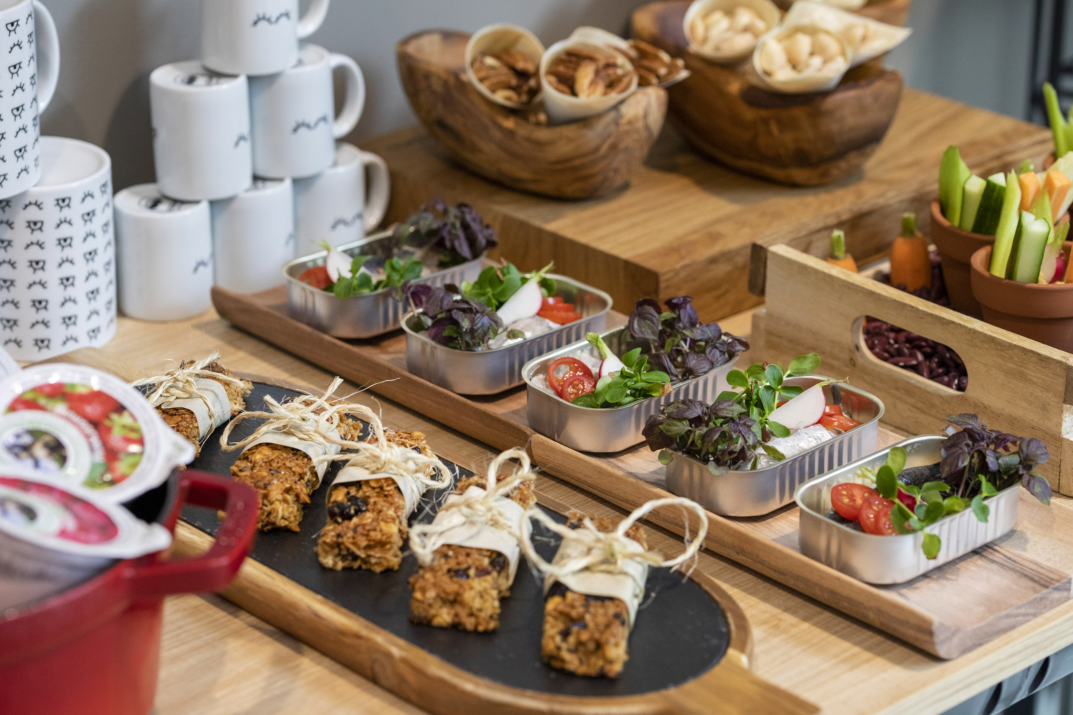 Healthy buffet: granola bars, mini salads, nuts, and fresh vegetables.