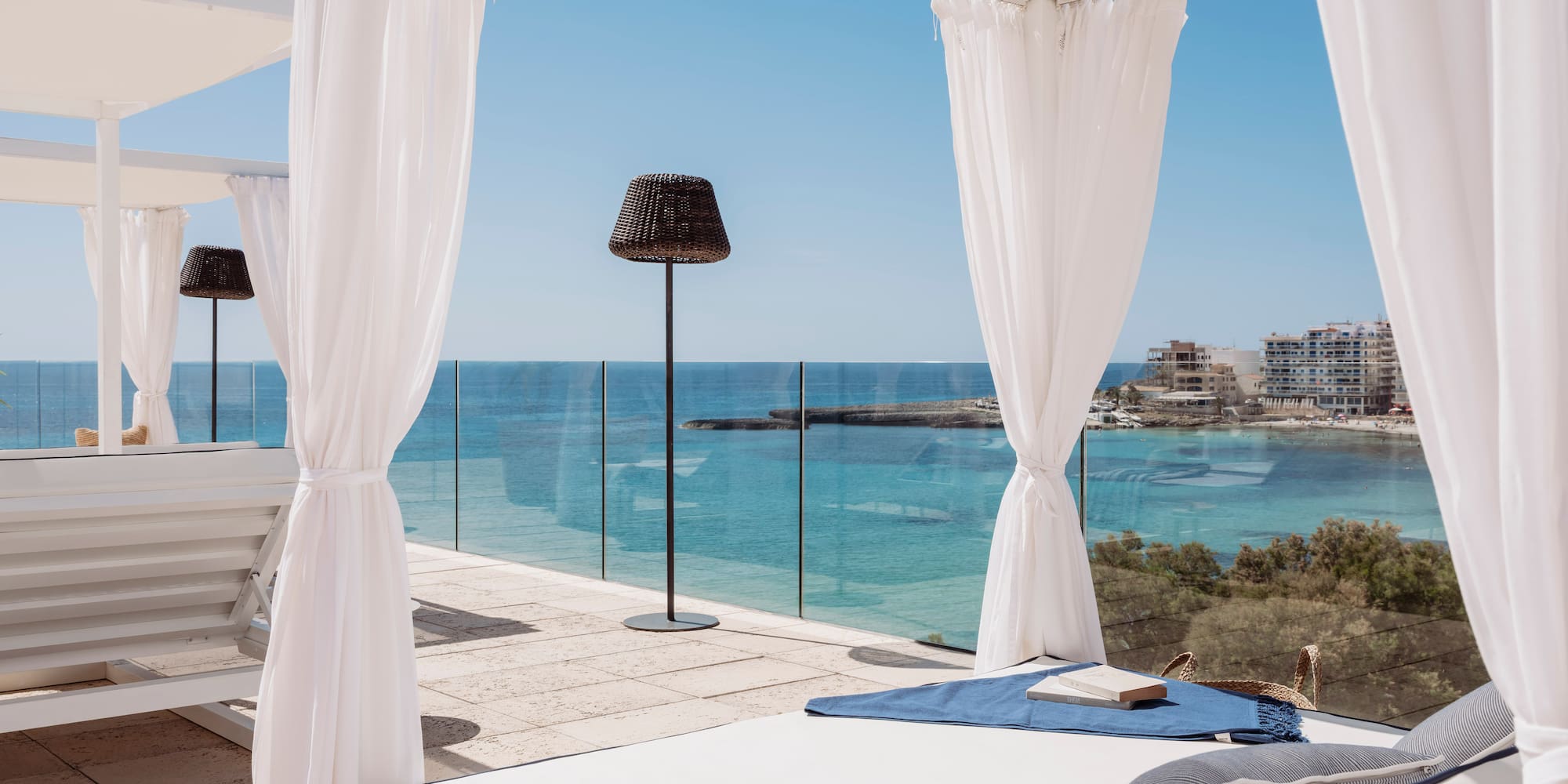 Cenador blanco con camastro y vistas al mar Mediterráneo.