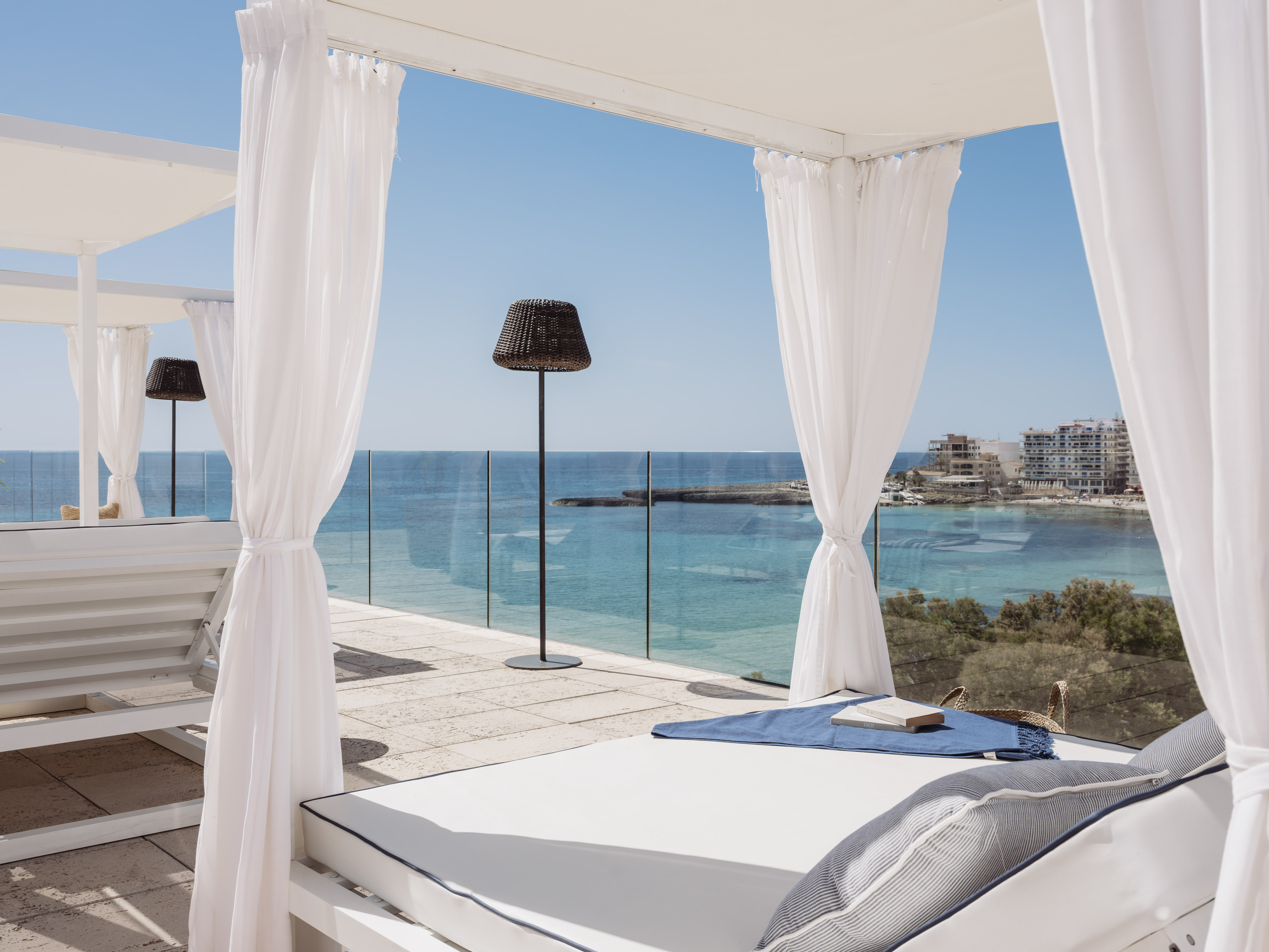 Cenador blanco con camastro y vistas al mar Mediterráneo.