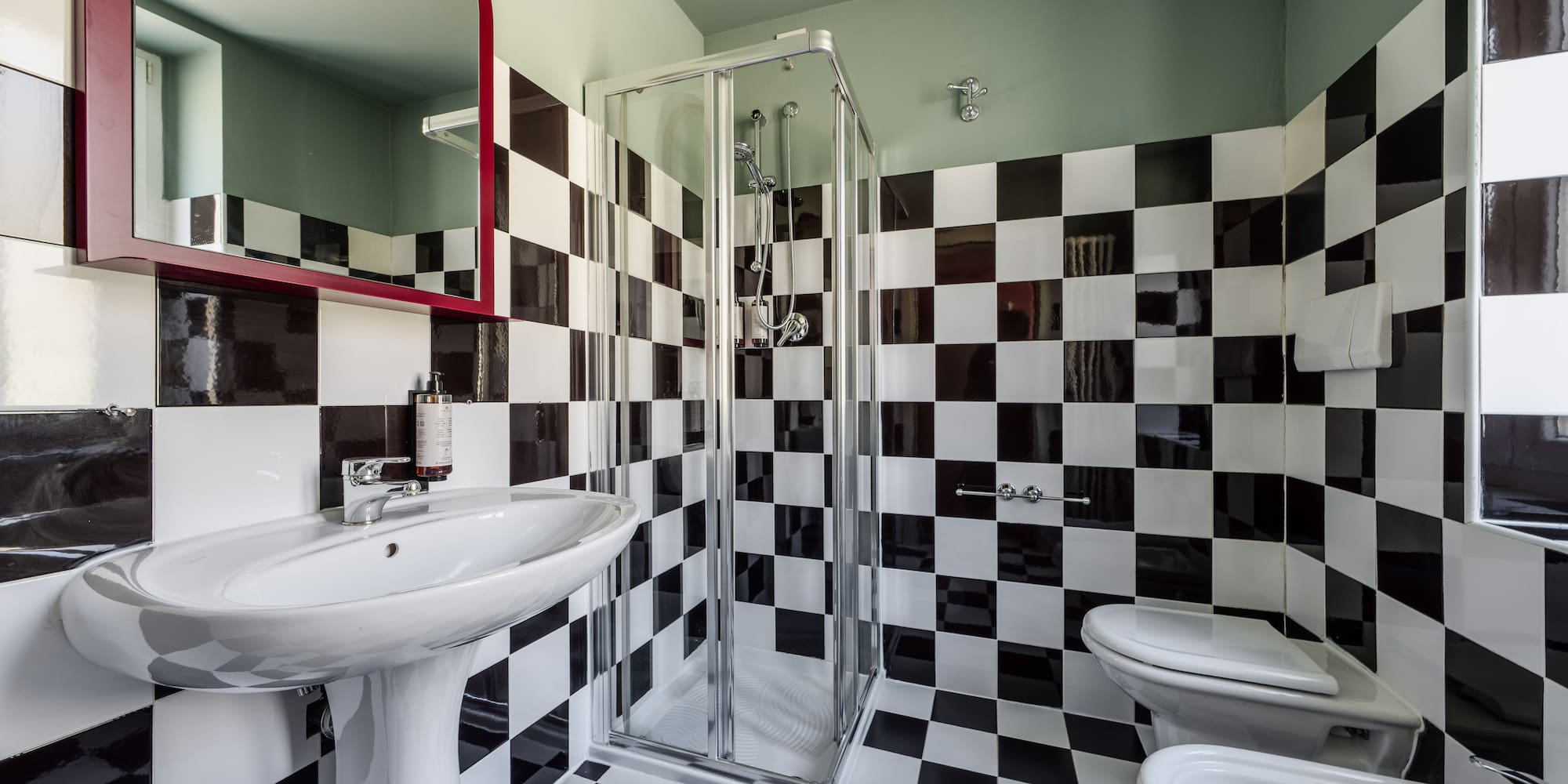 Black and white checkered bathroom with shower, sink, and toilet.