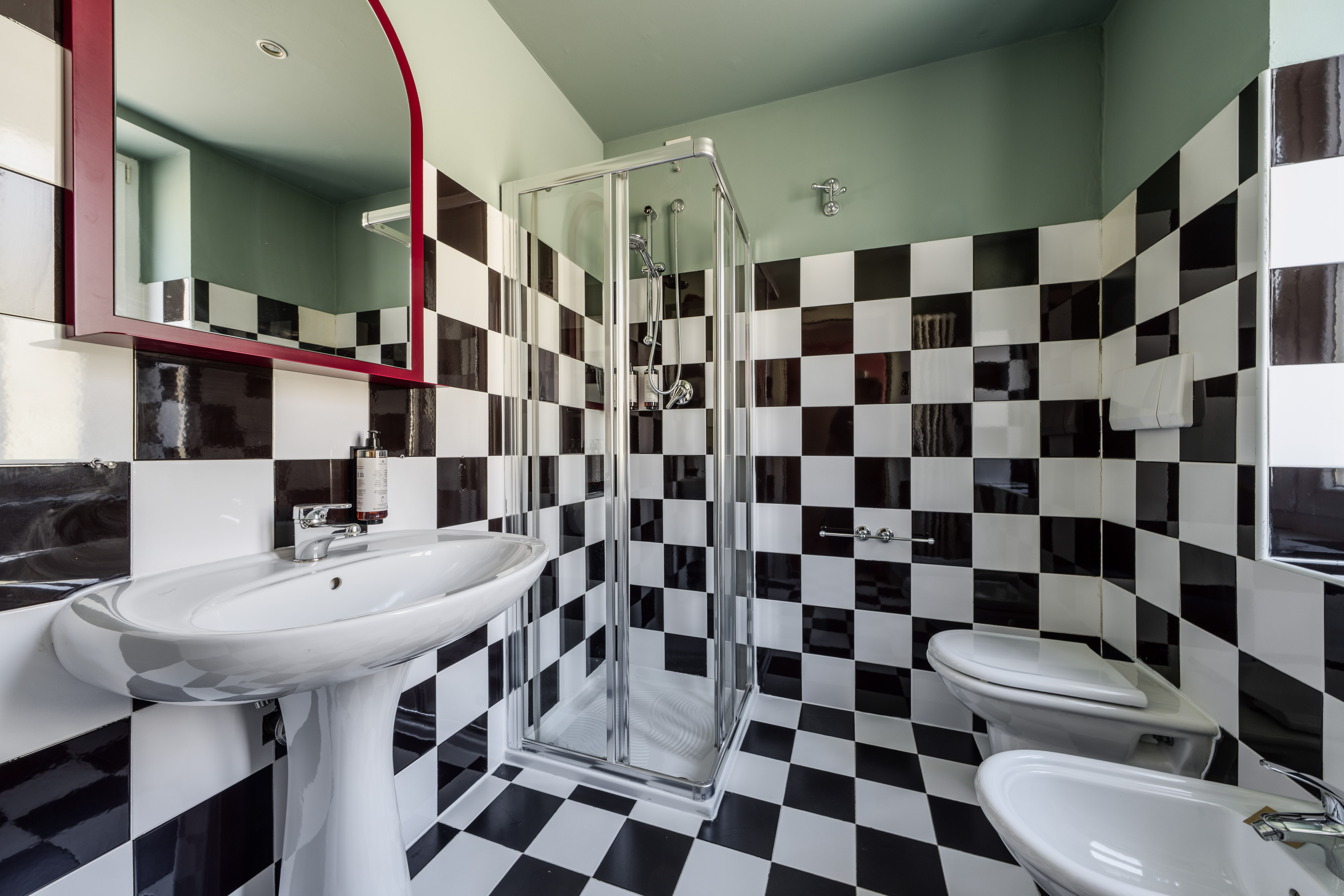 Black and white checkered bathroom with shower, sink, and toilet.