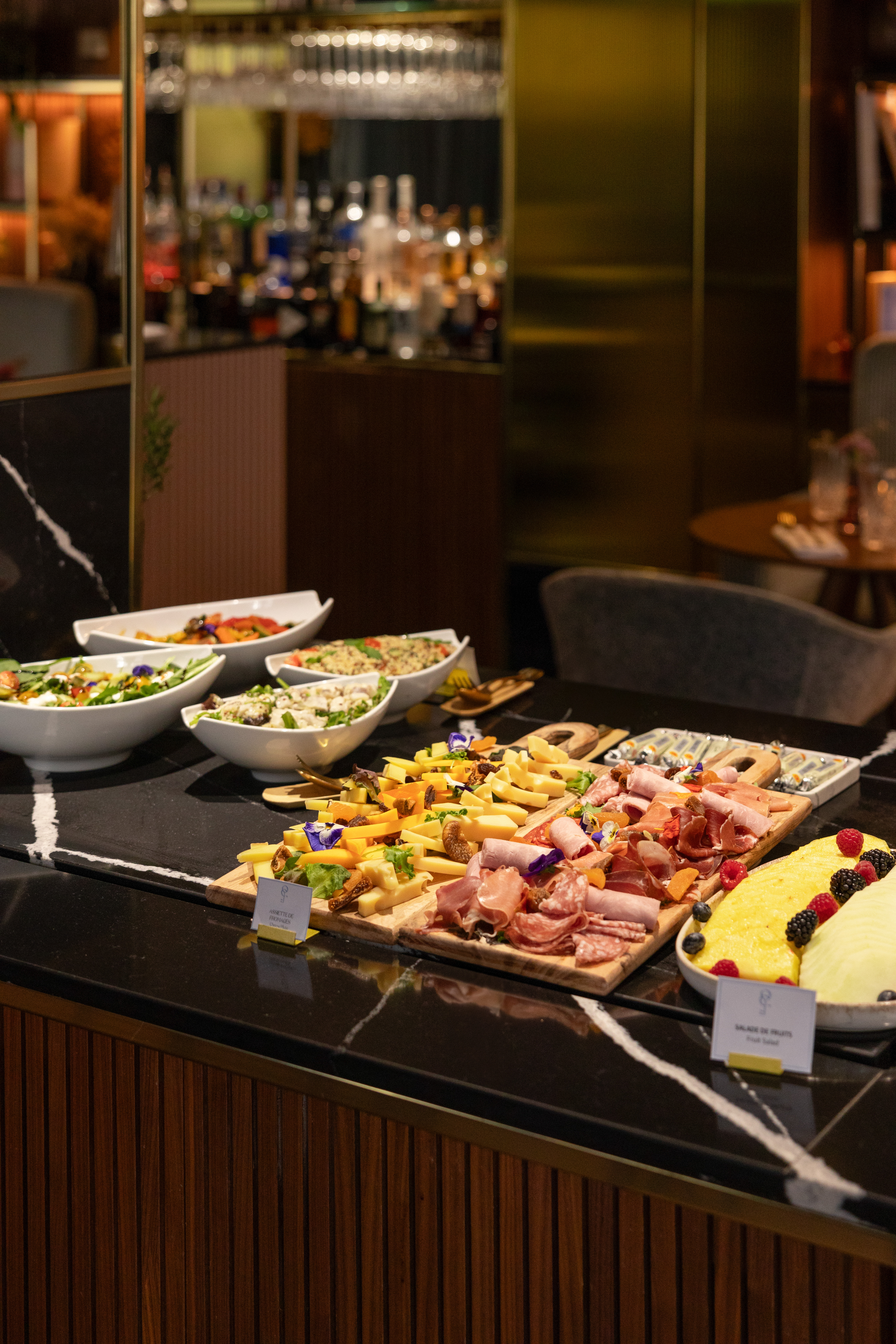 Diverse gourmet buffet with fresh salads, charcuterie, cheese, and fruit.