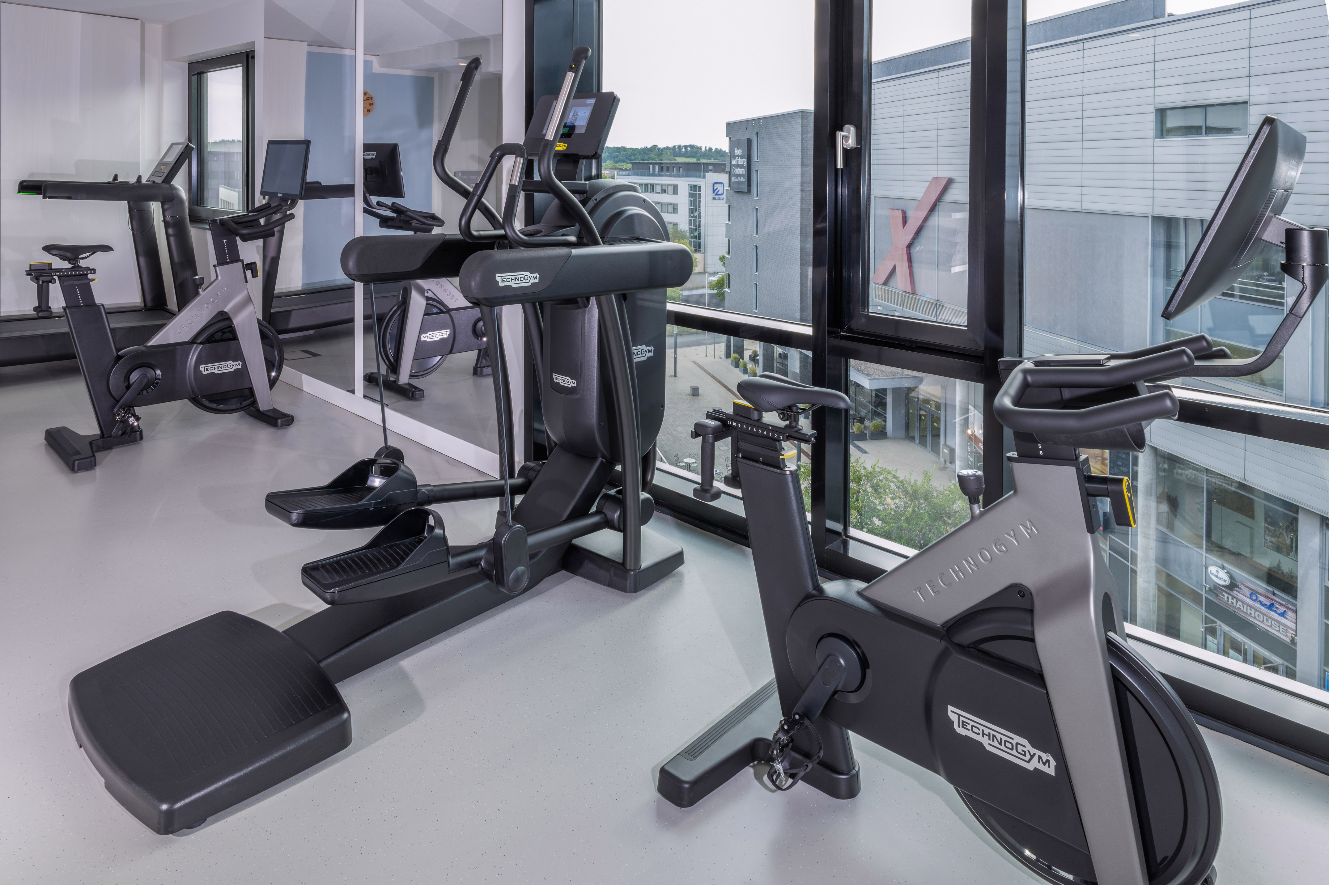 Modern hotel gym with Technogym treadmill, elliptical, and stationary bike. - Khu vực tập thể dục - INNSiDE Wolfsburg, Wolfsburg