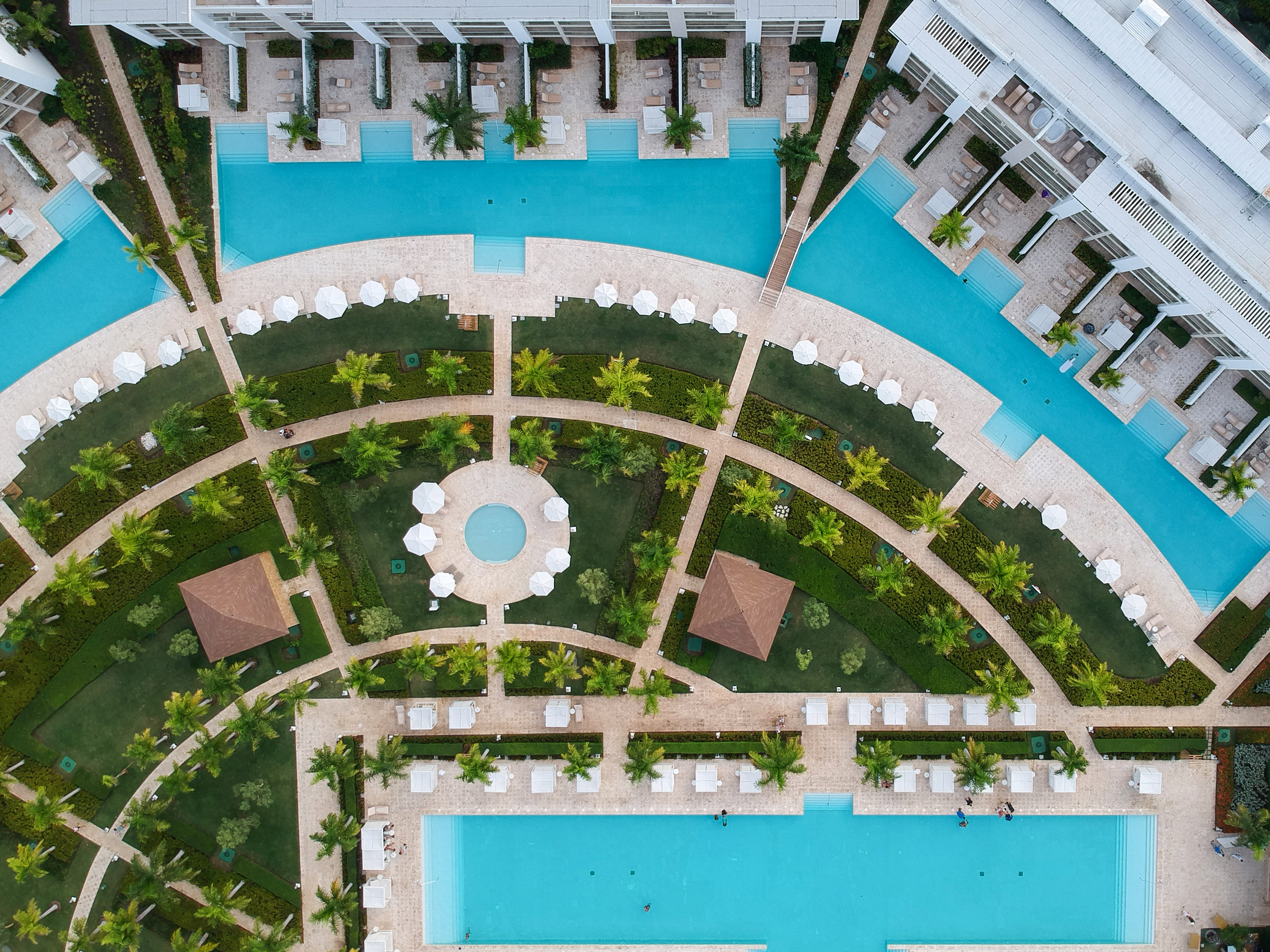 Aerial view luxury resort, multiple swimming pools, tropical landscaping, hotel buildings.