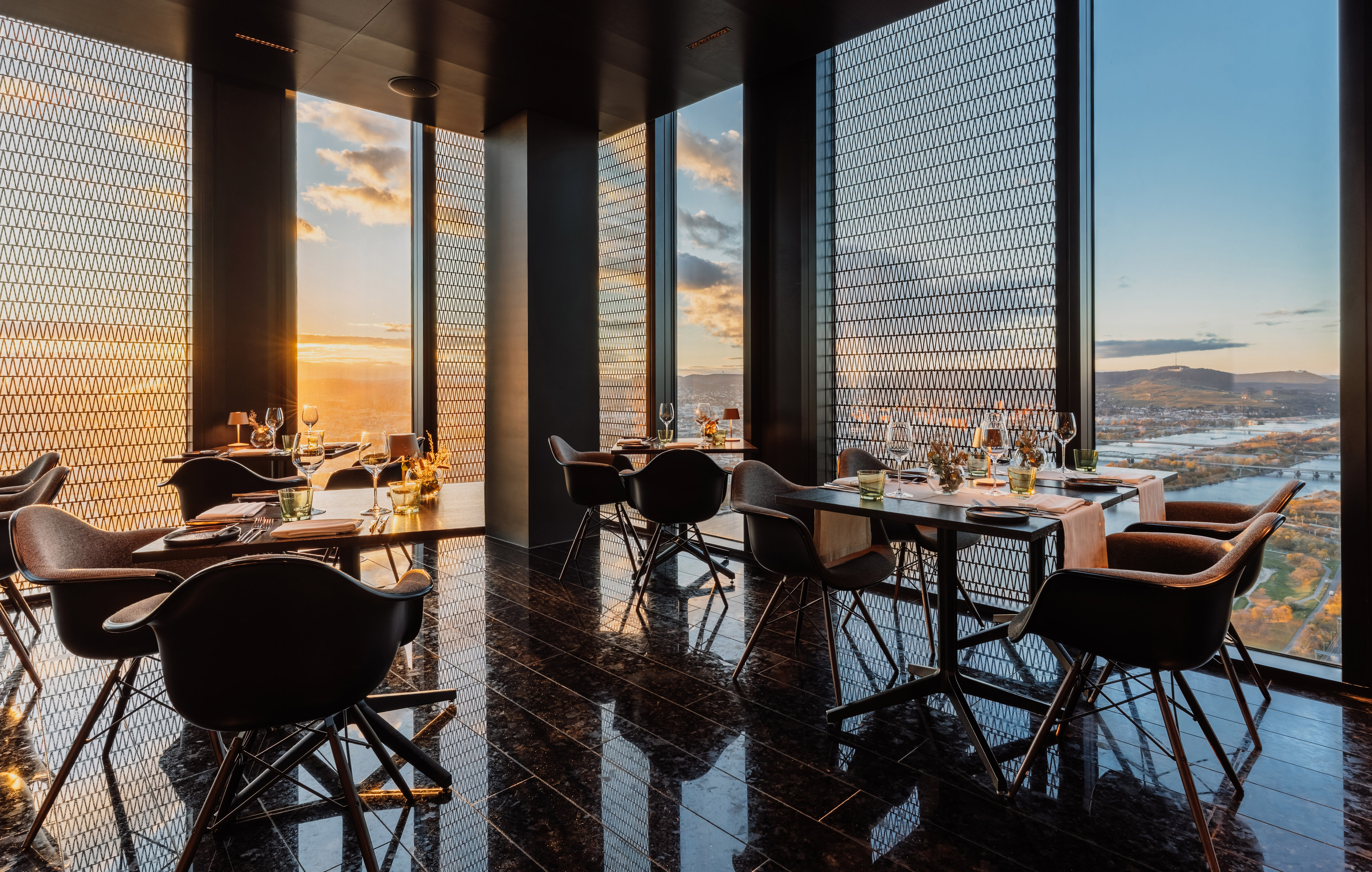 Luxury restaurant with panoramic sunset view over river and hills.