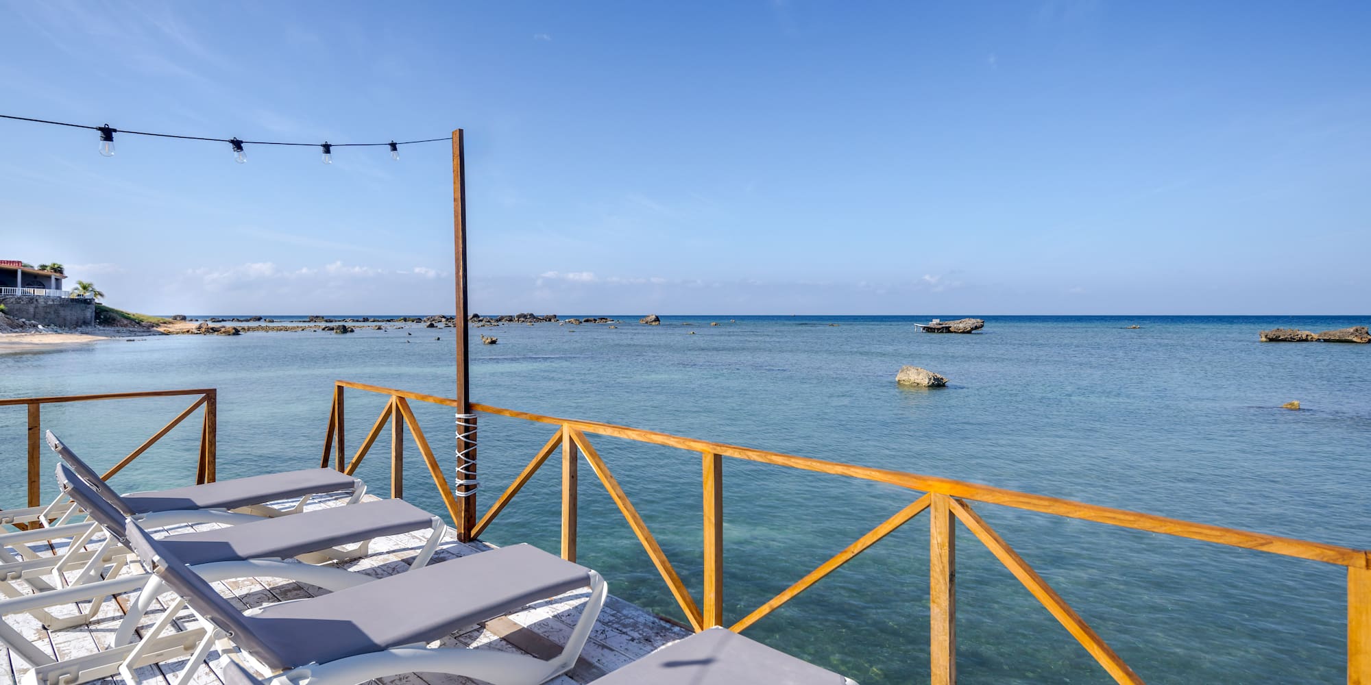 a deck with chairs and a railing overlooking the ocean