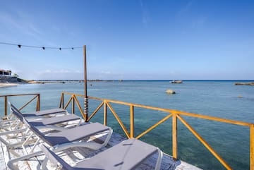 a deck with chairs and a railing overlooking the ocean