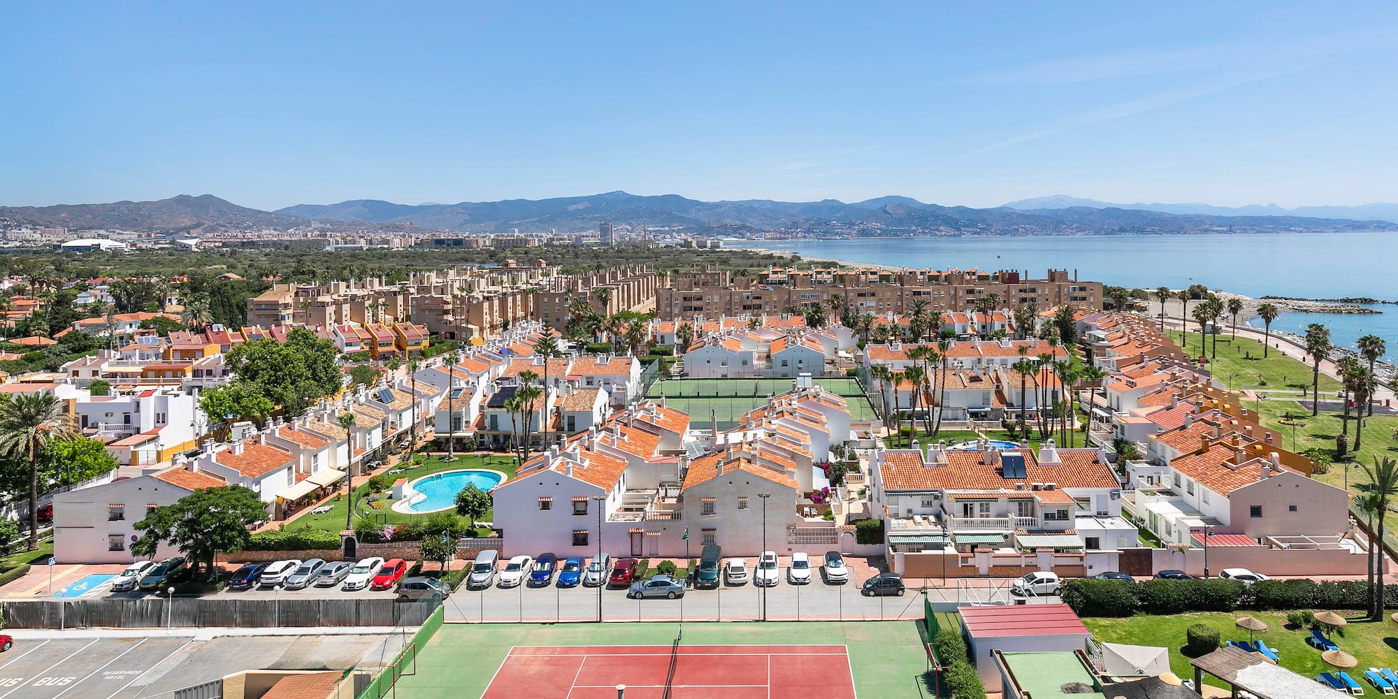 a tennis court and a city with a body of water in the background