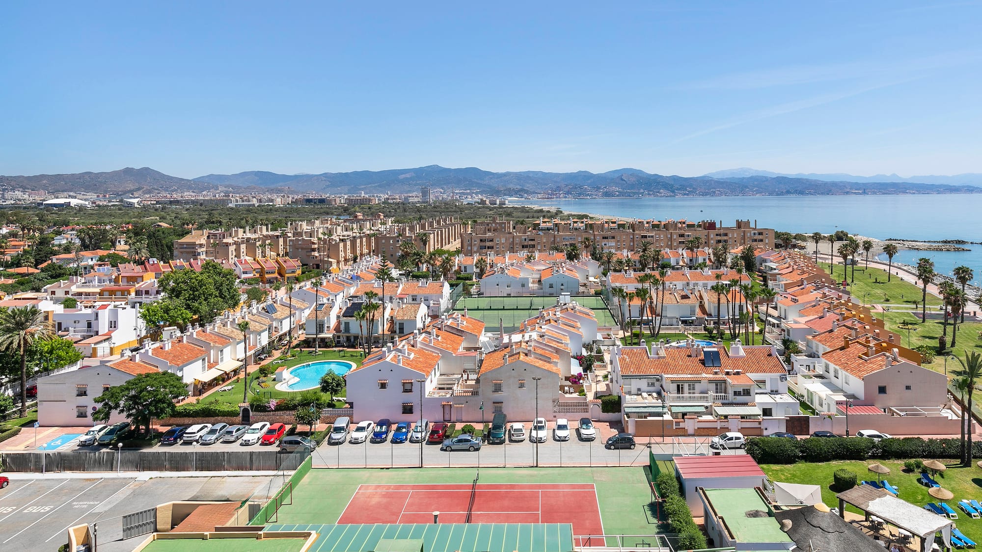 a tennis court and a city with a body of water in the background