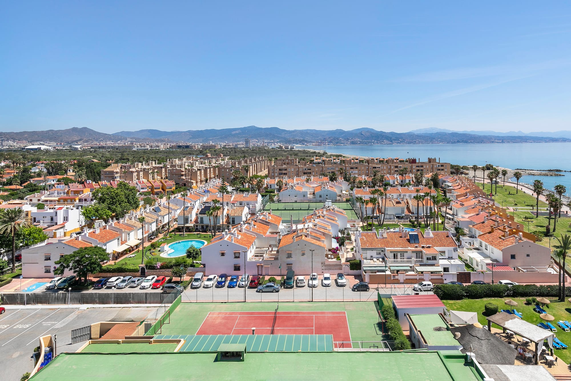 a tennis court and a city with a body of water in the background