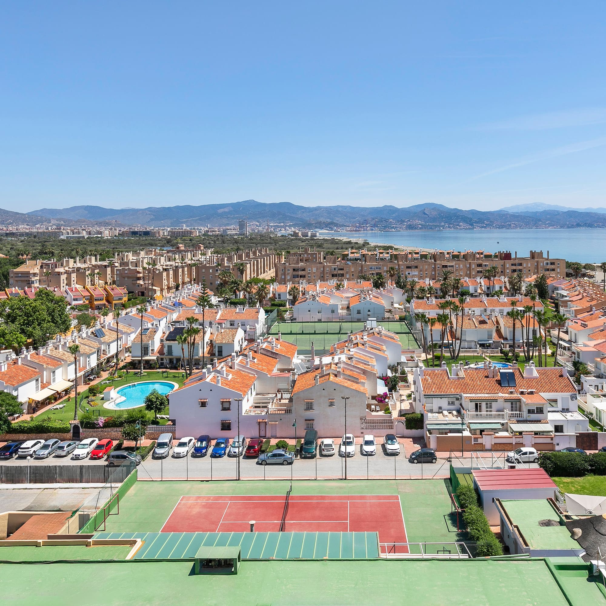 a tennis court and a city with a body of water in the background