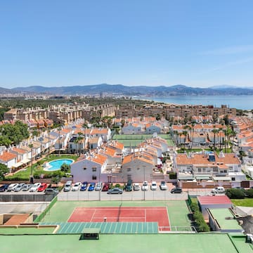 a tennis court and a city with a body of water in the background