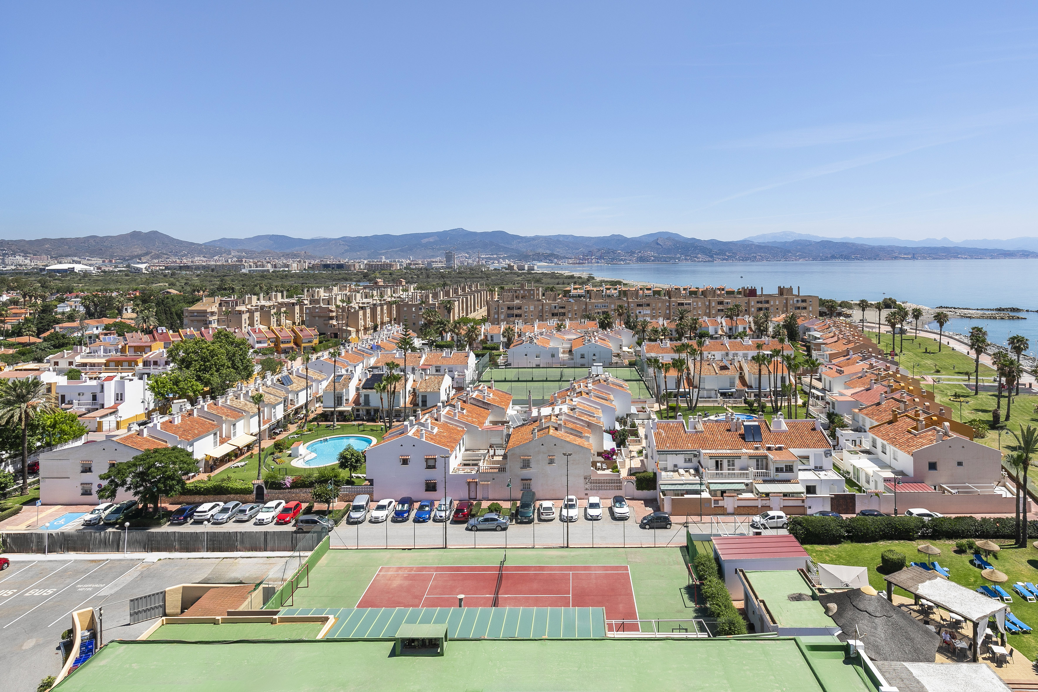 a tennis court and a city with a body of water in the background
