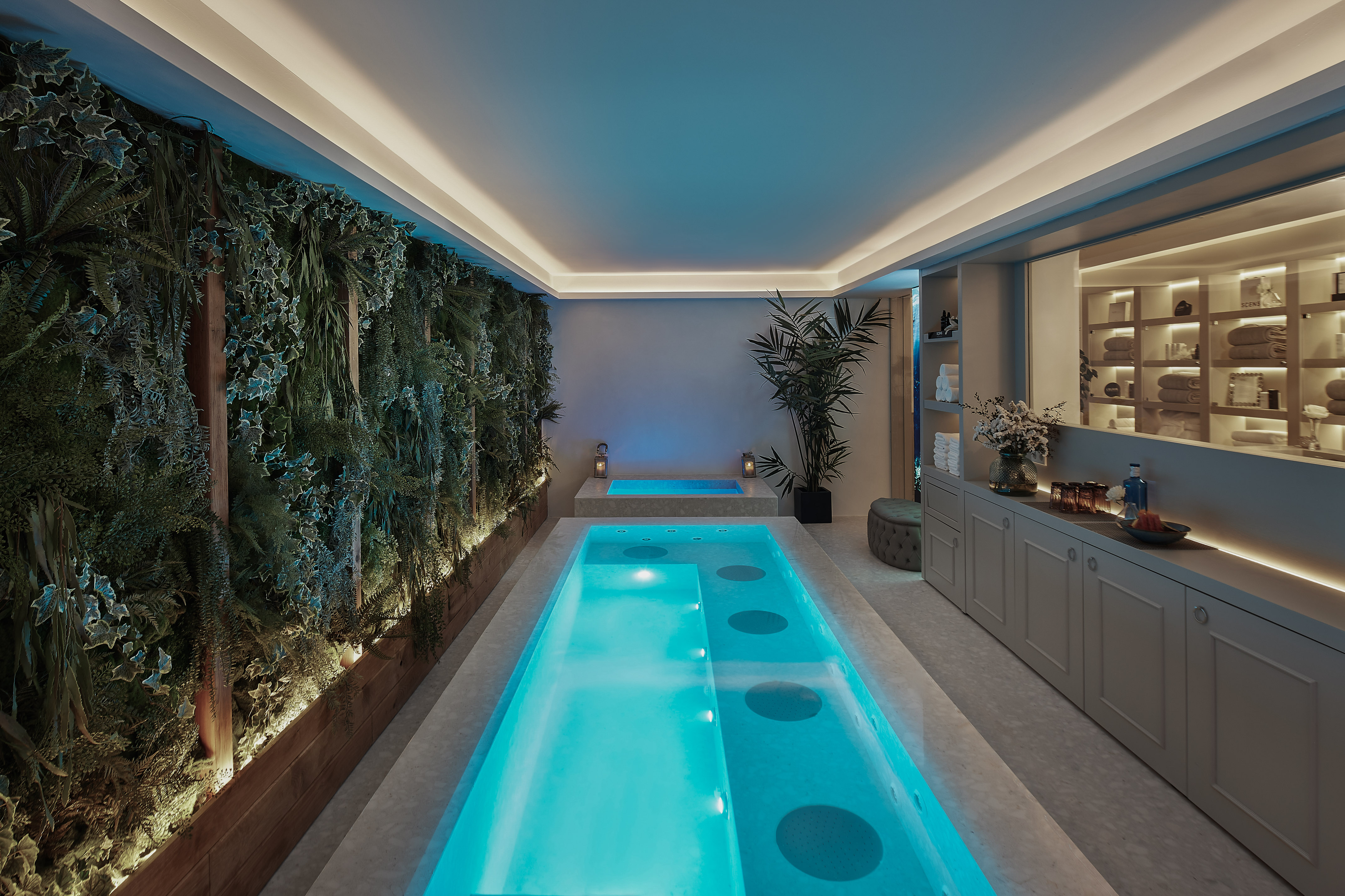 Indoor spa with blue-lit plunge pool, green living wall, and modern design.