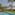 Luxury hotel private pool with tropical garden, palm trees, and thatched gazebo daybed.