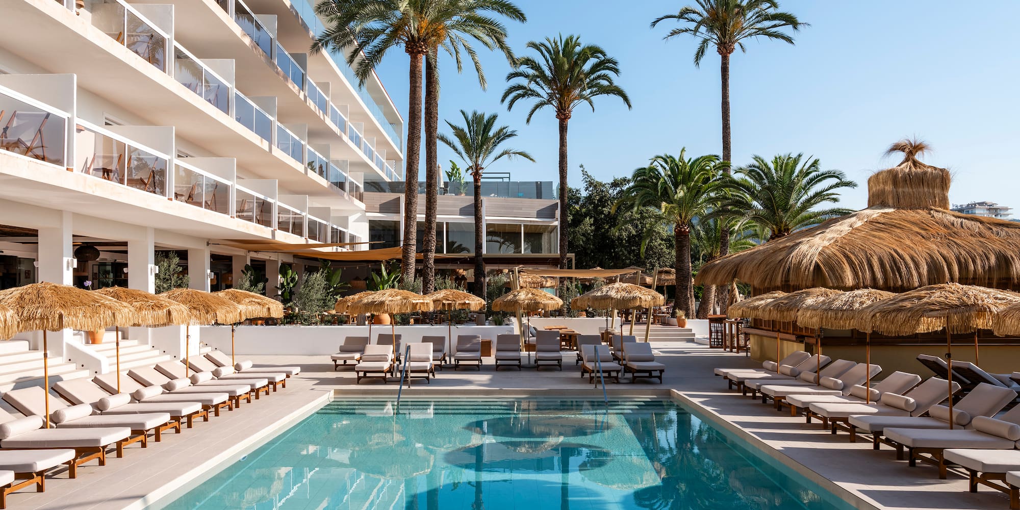 a pool with lounge chairs and umbrellas in front of a building
